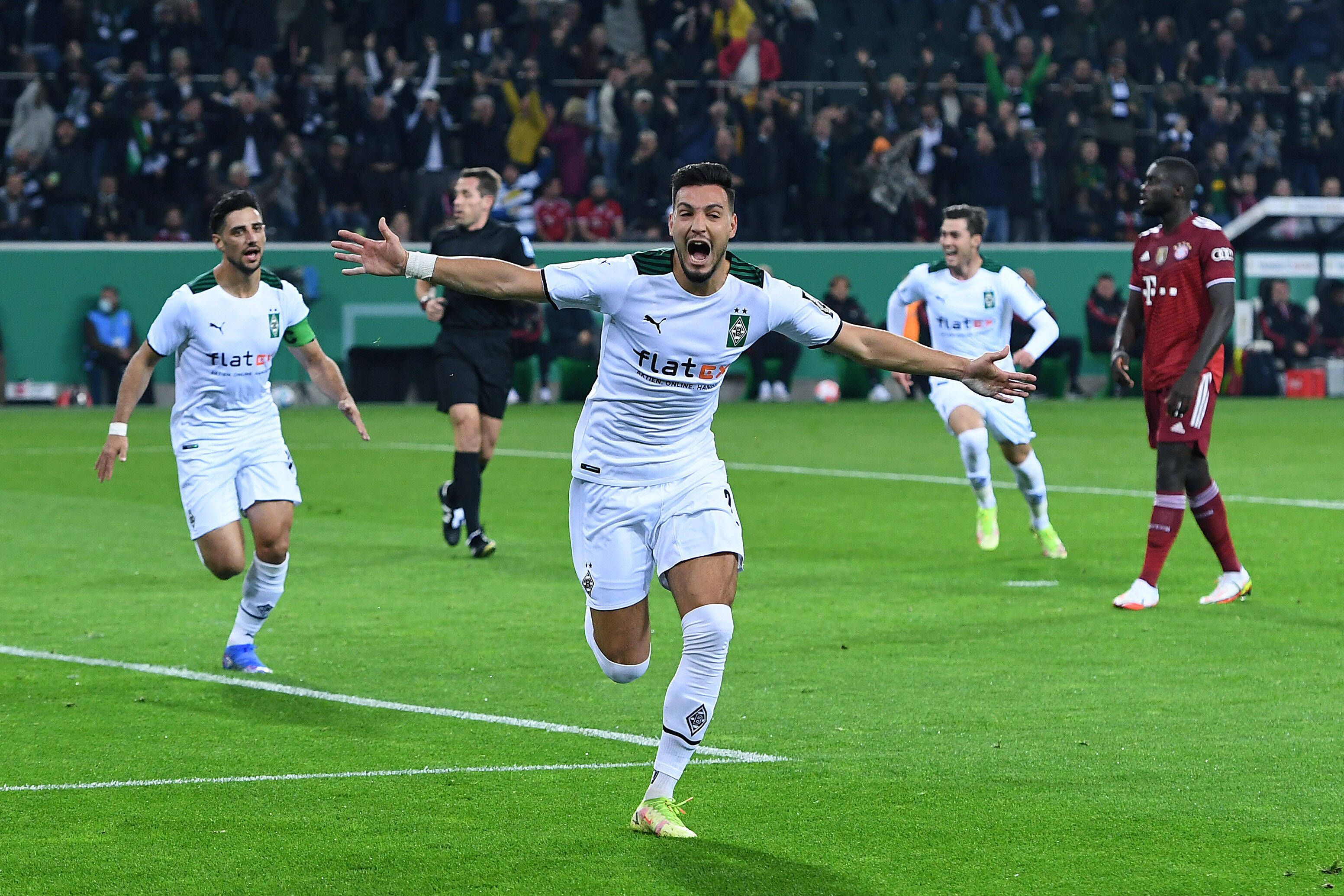 Ramy Bensebaini (M.) jubelt über einenTreffer für Borussia Mönchengladbach im DFB-Pokal-Spiel gegen Bayern München am 27. Oktober 2021 im Borussia-Park. Im Hintergrund jubeln auch Stindl und Scally.