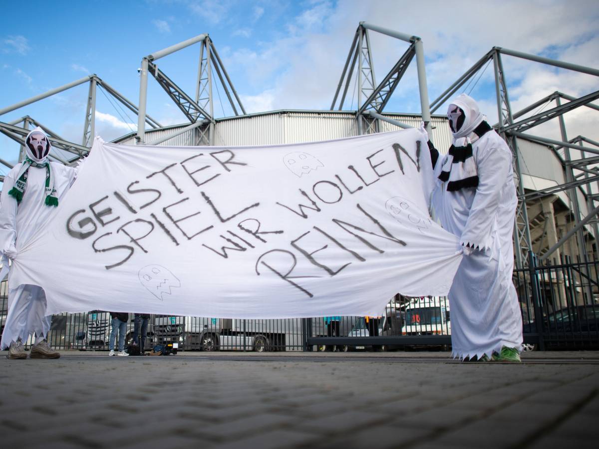 Zwei als Geist verkleidete Gladbach-Fans stehen vor dem Derby gegen den 1. FC Köln am 11. März 2020 vor den Toren des Borussia-Parks. Sie zeigen ein Banner mit der Aufschrift „Geisterspiel, wir wollen rein“.