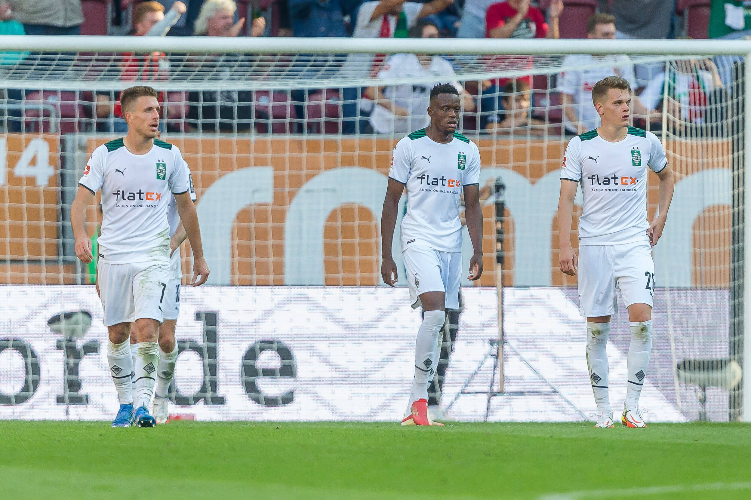 Patrick Herrmann (l.), Denis Zakaria (Mitte) und Matthias Ginter (r.) von Borussia Mönchengladbach verlassen nach der Auswärtsniederlage beim FC Augsburg am 18. September 2021 mit gesenkten Köpfen den Platz der WWK-Arena.