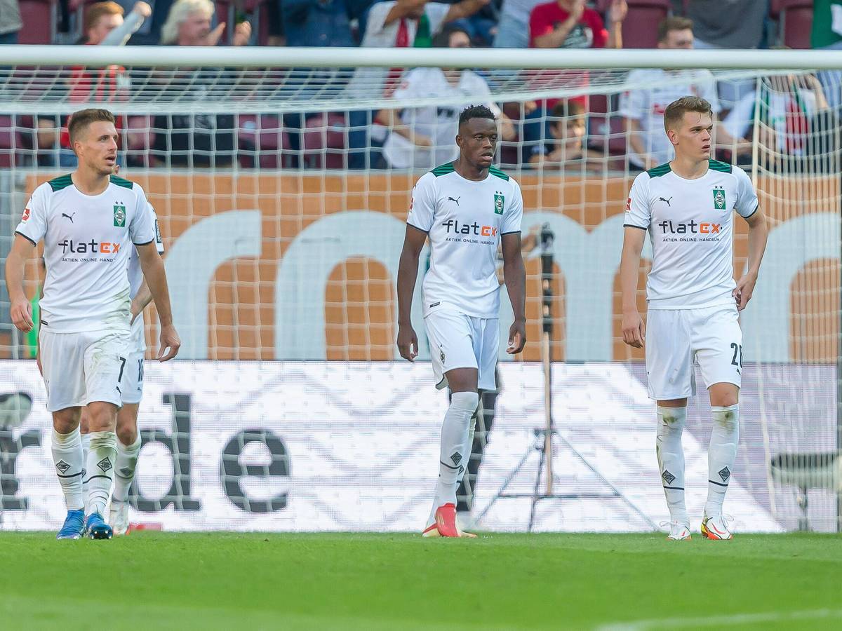 Patrick Herrmann (l.), Denis Zakaria (Mitte) und Matthias Ginter (r.) von Borussia Mönchengladbach verlassen nach der Auswärtsniederlage beim FC Augsburg am 18. September 2021 mit gesenkten Köpfen den Platz der WWK-Arena.