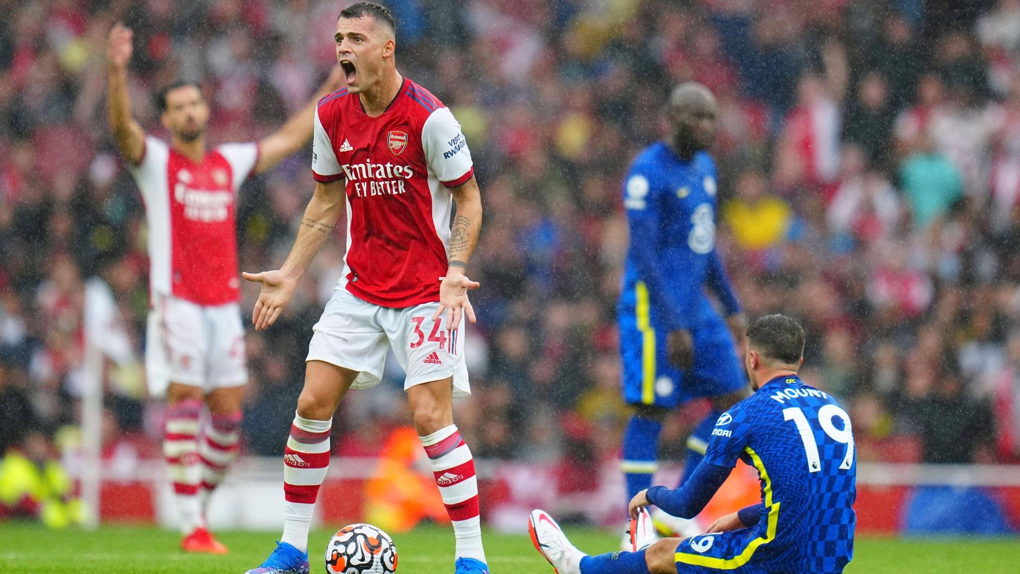 Granit Xhaka (l.), ehemaliger Kapitän von Fußball-Bundesligist Borussia Mönchengladbach, im Trikot von Arsenal London am 22. August 2021 im Premier-League-Duell gegen den FC Chelsea. Xhaka brüllt seinen Unmut heraus und gestikuliert.