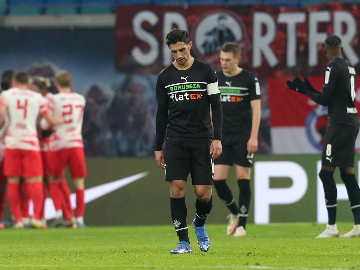 Enttäuschung bei den Gladbach-Profis um Kapitän Lars Stindl, im Hintergrund jubeln die die Leipziger über einen Treffer im Bundesliga-Duell am 11. Dezember 2021 in der RB-Arena. Lars Stindl schaut niedergeschlagen auf den Boden.