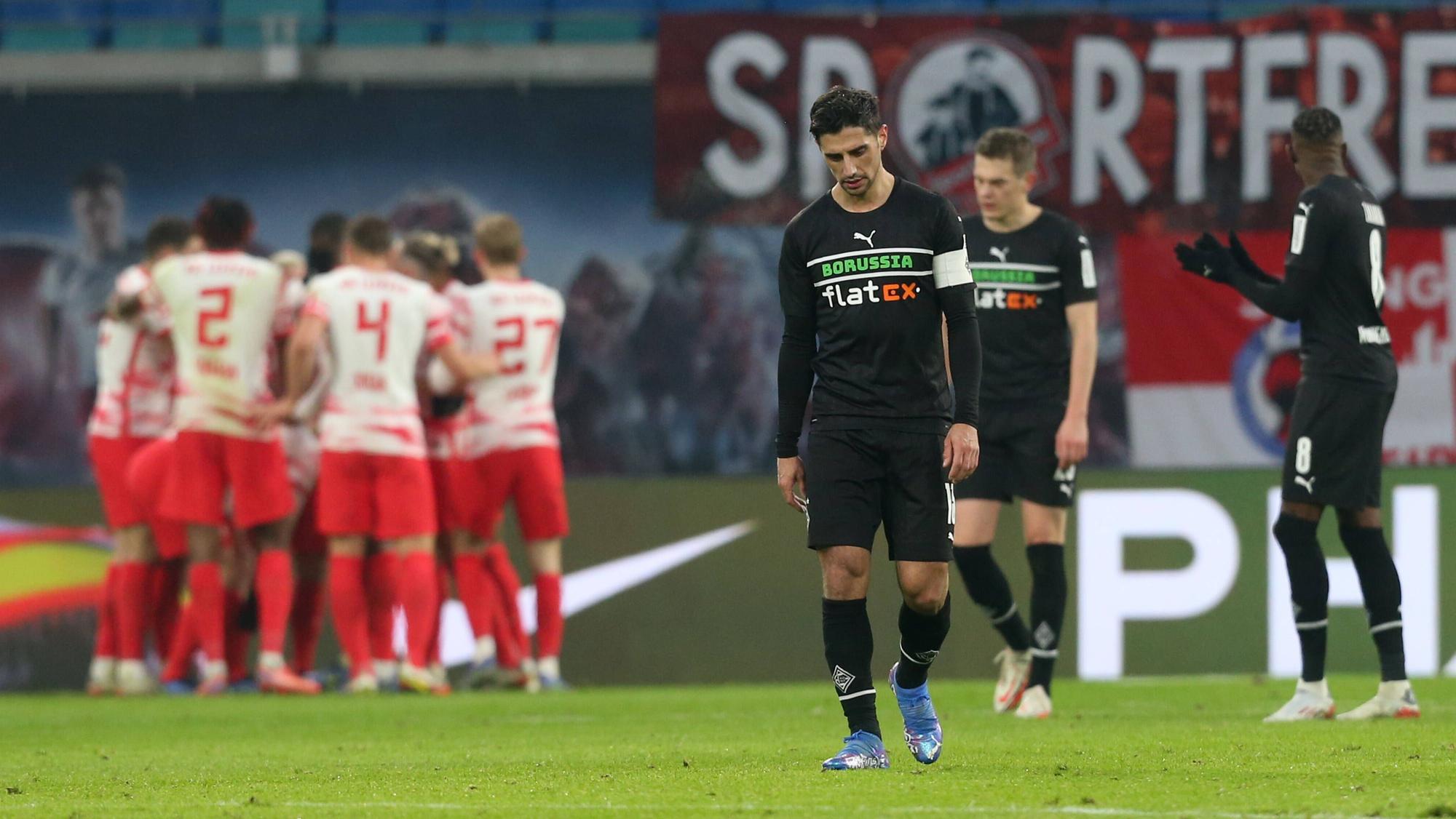 Enttäuschung bei den Gladbach-Profis um Kapitän Lars Stindl, im Hintergrund jubeln die die Leipziger über einen Treffer im Bundesliga-Duell am 11. Dezember 2021 in der RB-Arena. Lars Stindl schaut niedergeschlagen auf den Boden.