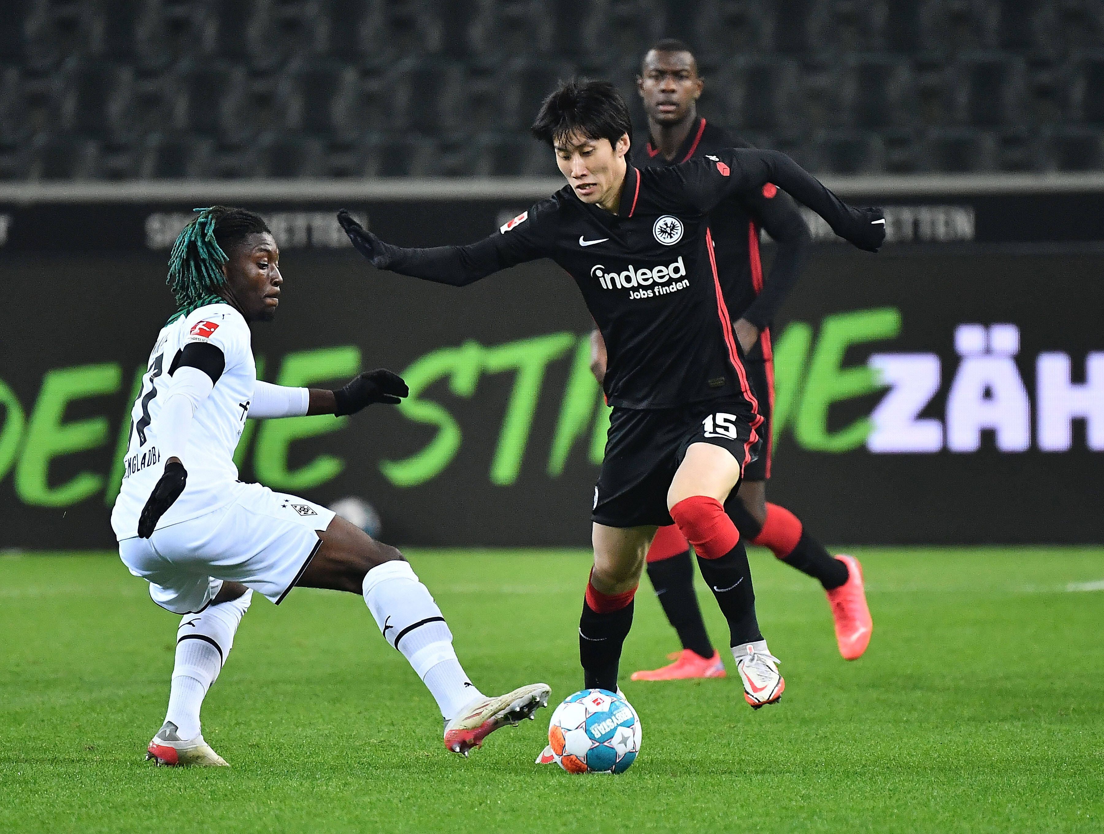 Manu Kone (l.) von Borussia Mönchengladbach versucht gegen Daichi Kamada (r.) von Eintracht Frankfurt an den Ball zu kommen, am 15. Dezember 2021.