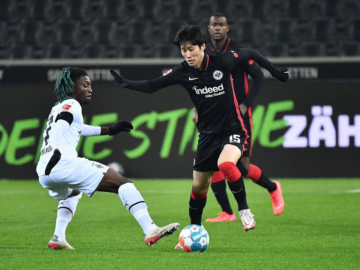 Manu Kone (l.) von Borussia Mönchengladbach versucht gegen Daichi Kamada (r.) von Eintracht Frankfurt an den Ball zu kommen, am 15. Dezember 2021.