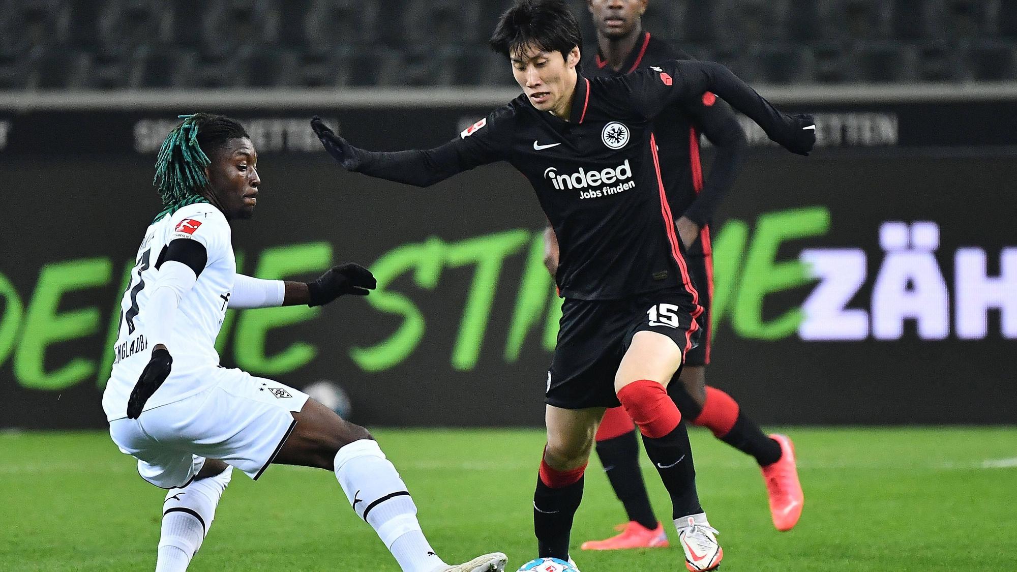 Manu Kone (l.) von Borussia Mönchengladbach versucht gegen Daichi Kamada (r.) von Eintracht Frankfurt an den Ball zu kommen, am 15. Dezember 2021.