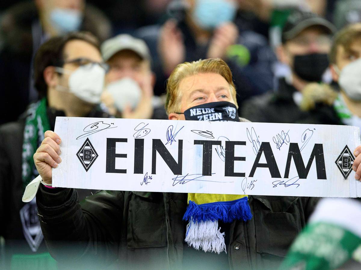 Ein Fan von Fußball-Bundesligist Borussia Mönchengladbach zeigt ein Plakat mit der Aufschrift „Ein Team“. Dieses Foto aus dem Borussia-Park ist am 5. Dezember 2021 entstanden.