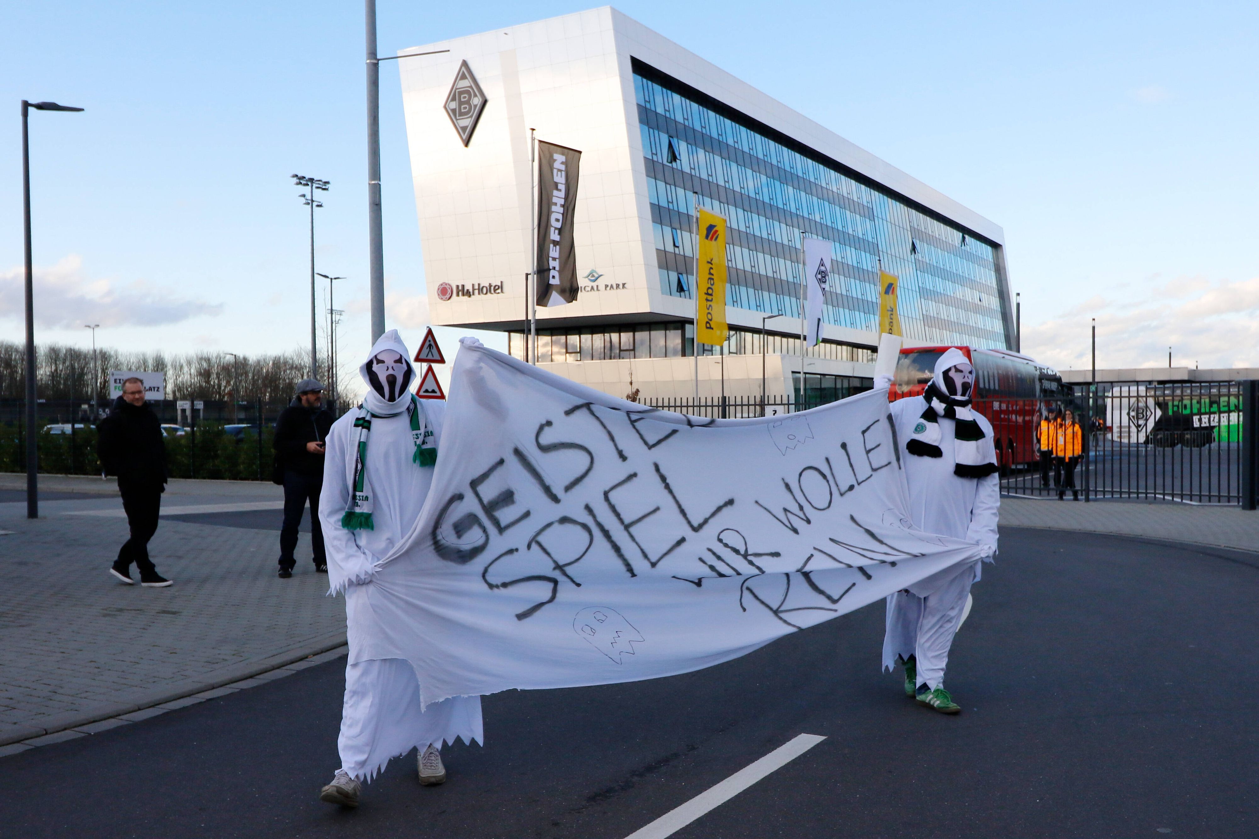 Als Geister verkleidete Gladbach-Fans halten am 11. März 2021 auf dem Gelände im Borussia-Park ein Transparent mit der Aufschrift: "Geisterspiel - Wir wollen rein" hoch.