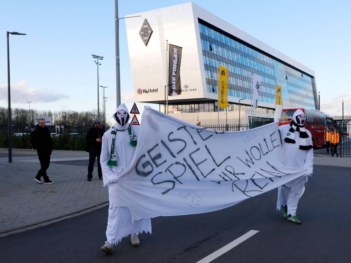 Als Geister verkleidete Gladbach-Fans halten am 11. März 2021 auf dem Gelände im Borussia-Park ein Transparent mit der Aufschrift: "Geisterspiel - Wir wollen rein" hoch.