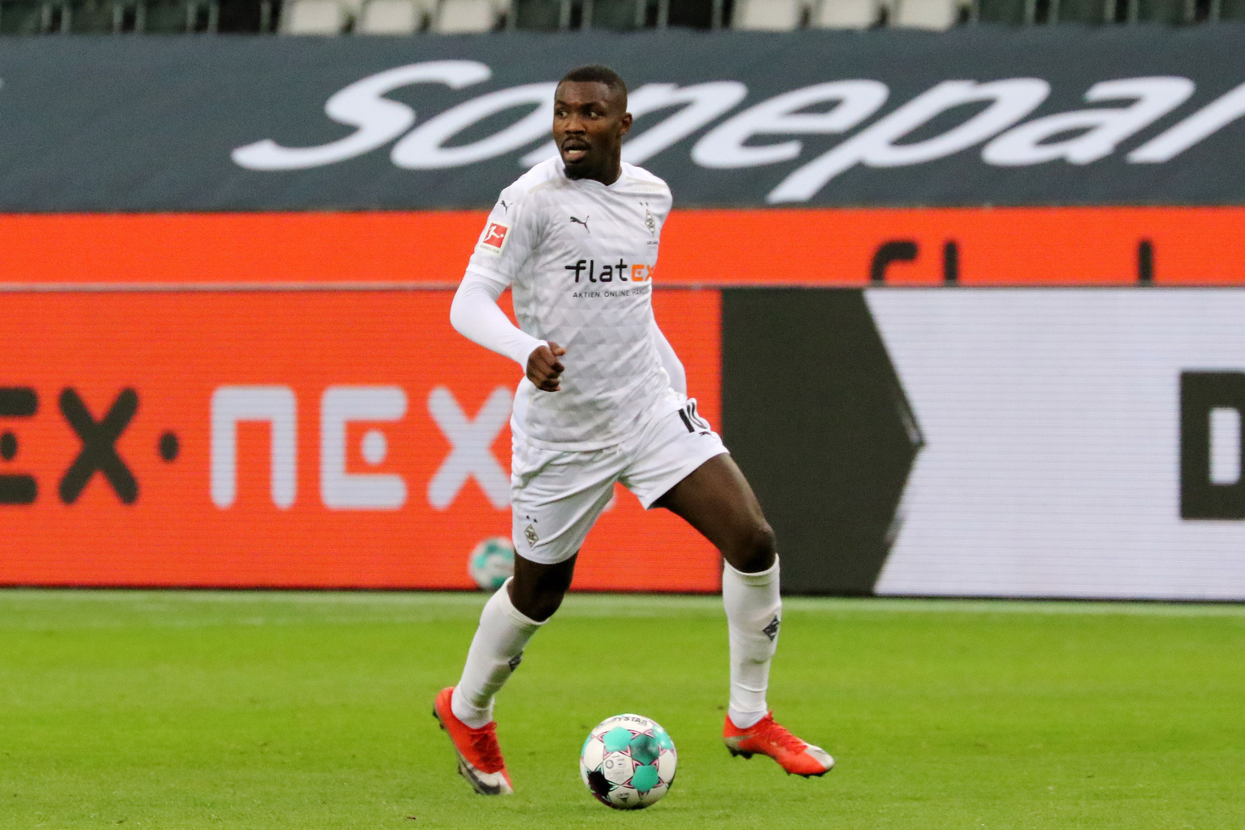 Gladbach-Stürmer Marcus Thuram, hier am 19. Dezember 2020 im Bundesliga-Duell gegen Hoffenheim zu sehen, blickt auf das Spielfeld und kontrolliert derweil den Ball.