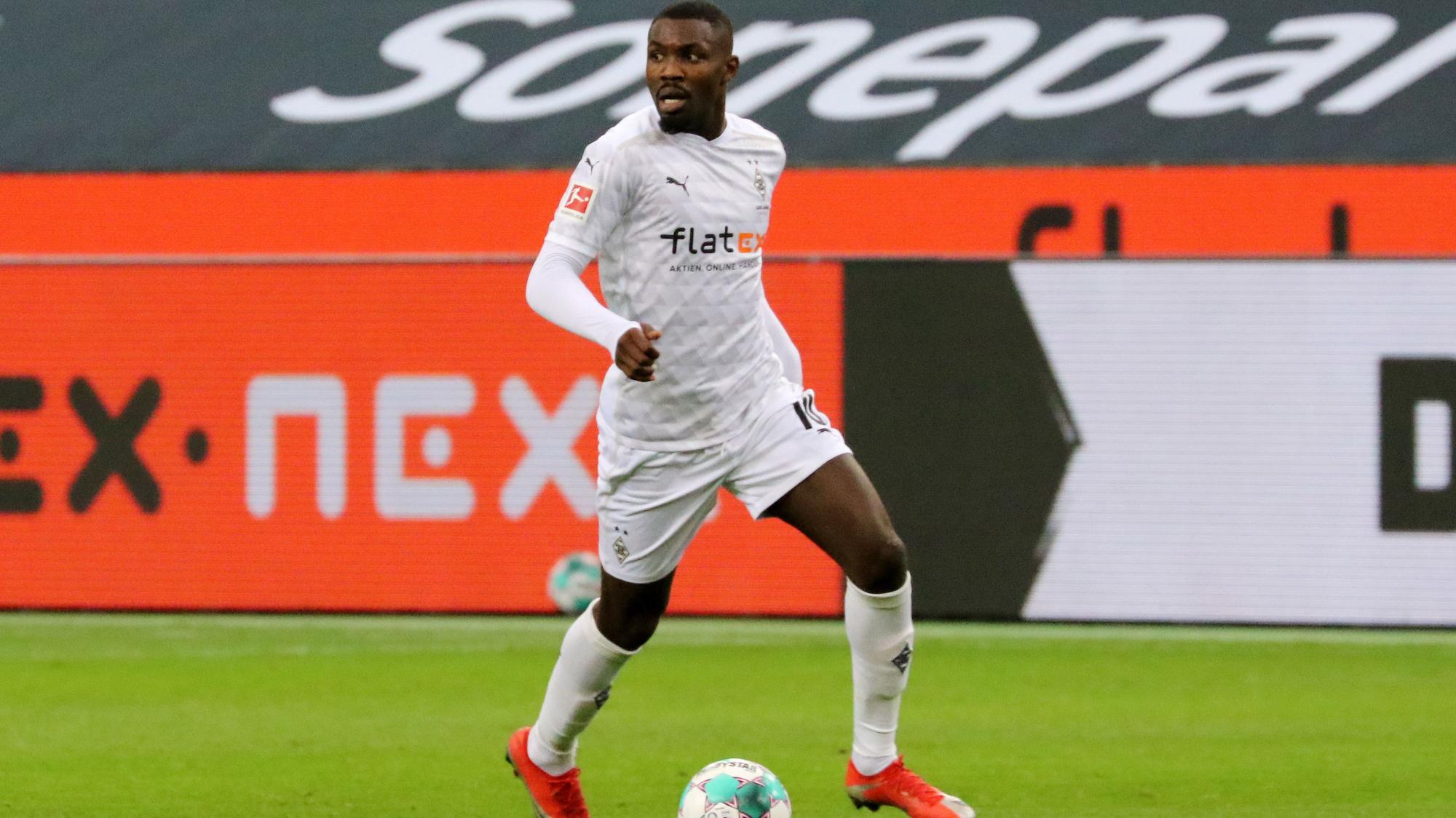 Gladbach-Stürmer Marcus Thuram, hier am 19. Dezember 2020 im Bundesliga-Duell gegen Hoffenheim zu sehen, blickt auf das Spielfeld und kontrolliert derweil den Ball.