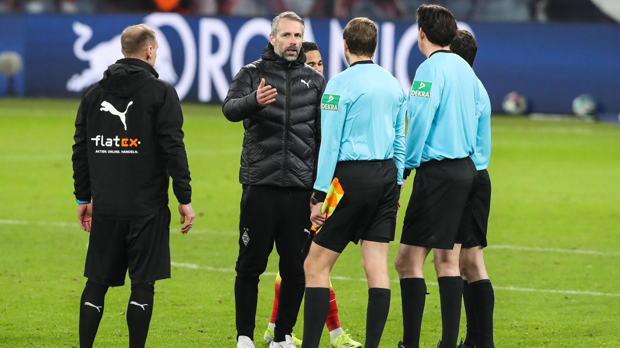 Gladbach-Trainer Marco Rose (M.) diskutiert mit Schiedsrichter Manuel Gräfe nach dem verlorenen Bundesliga-Topspiel (27. Februar 2021) bei RB Leipzig. Rose gestikuliert und spricht. Sein Assistent Alexander Zickler (l.) schaut zu.