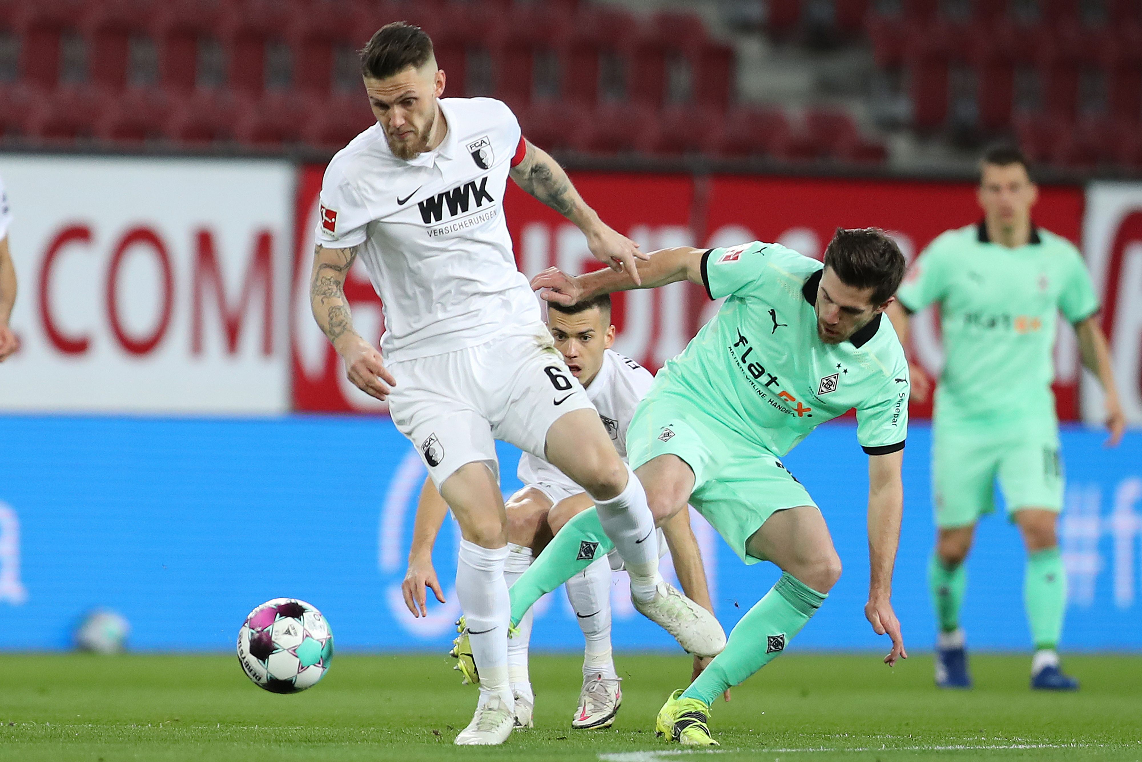 Borussias Jonas Hofmann im Zweikampf mit Augsburgs Jeffrey Gouweleeuw beim Bundesliga-Duell am 12. März 2021.