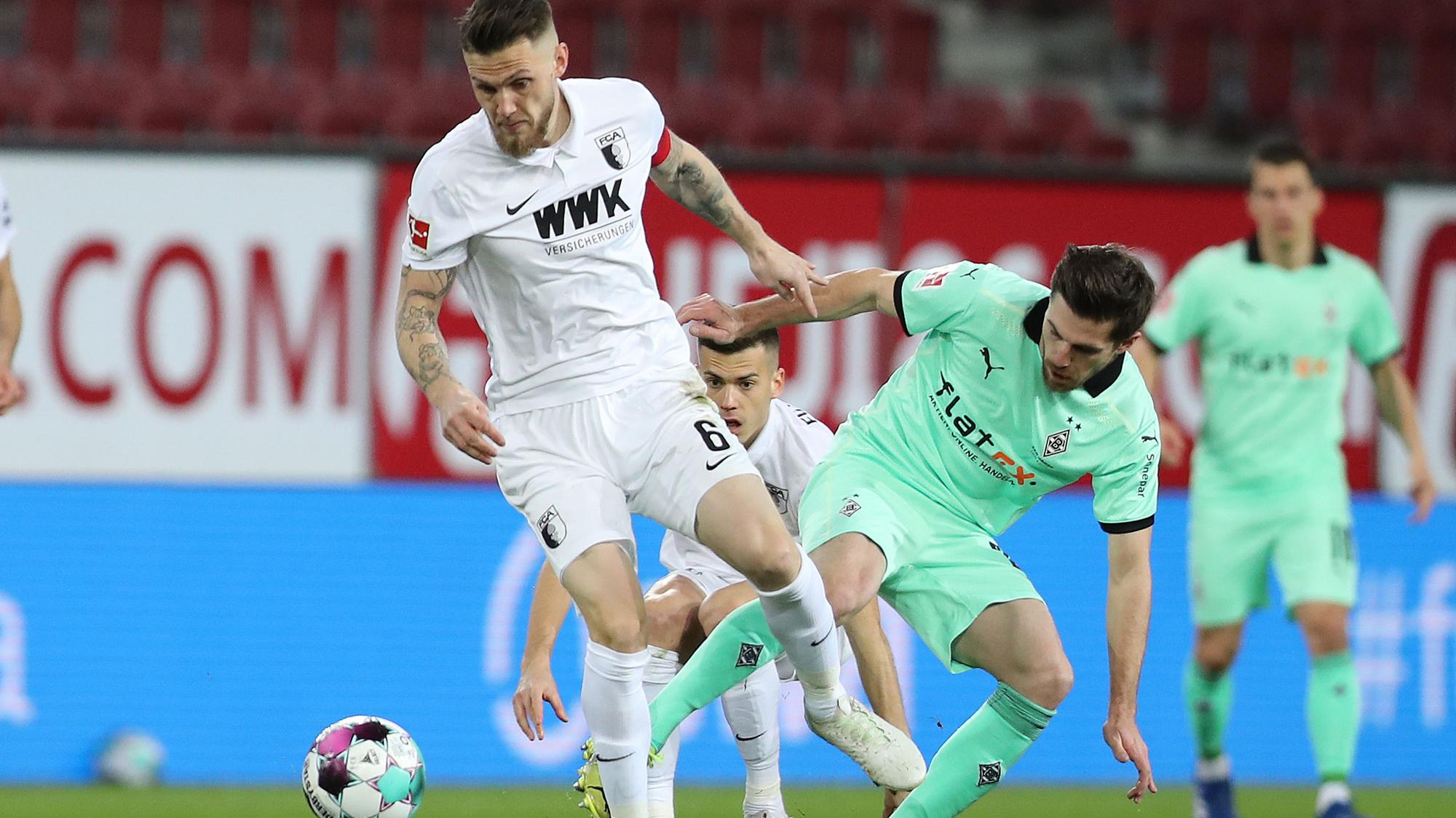 Borussias Jonas Hofmann im Zweikampf mit Augsburgs Jeffrey Gouweleeuw beim Bundesliga-Duell am 12. März 2021.