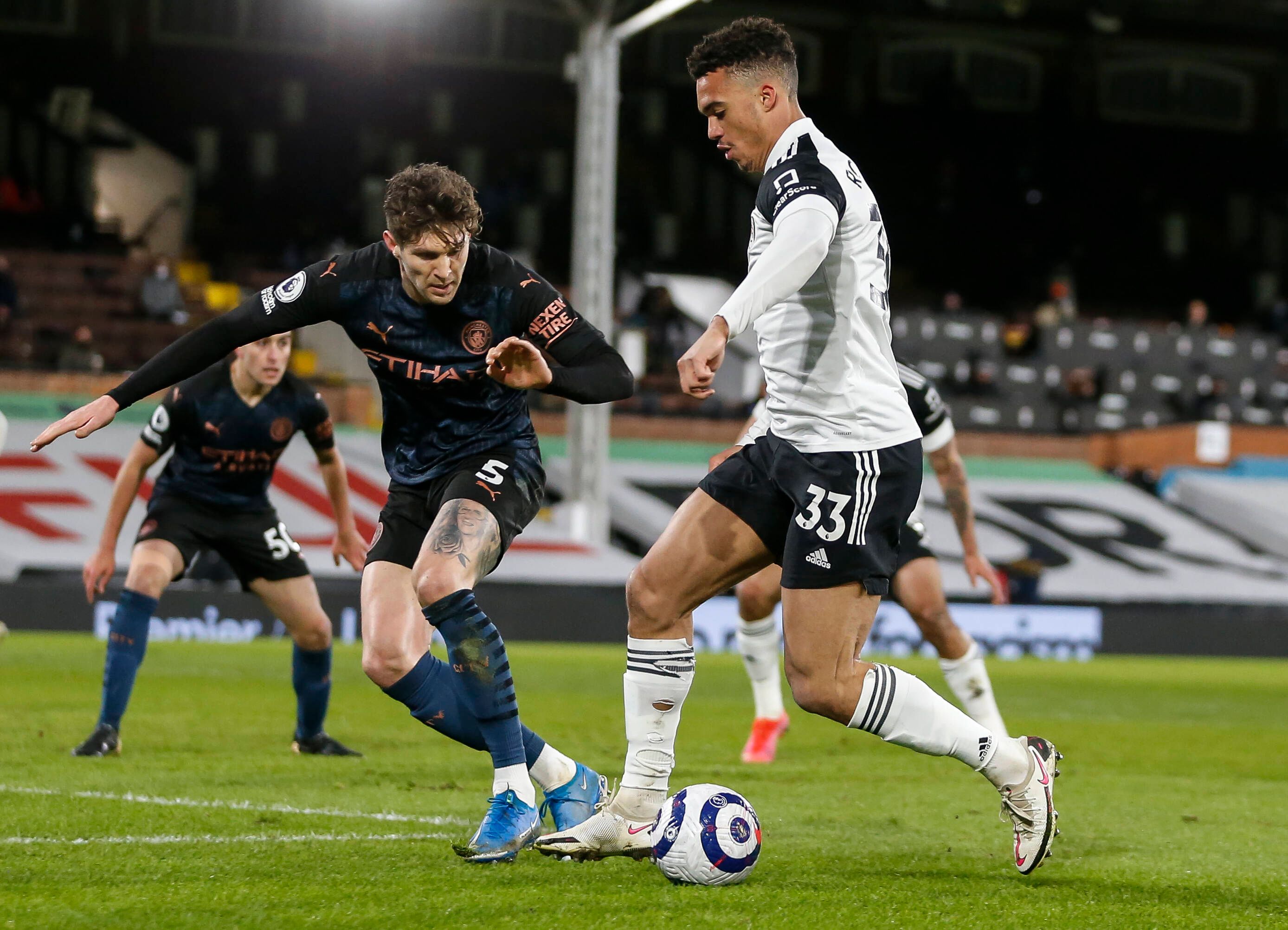 Fulhams Antonee Robinson (r) im Duell mit Manchester Citys John Stones während des Premier-League-matchs zwischen Fulham and Manchester City am 13. März 2021.