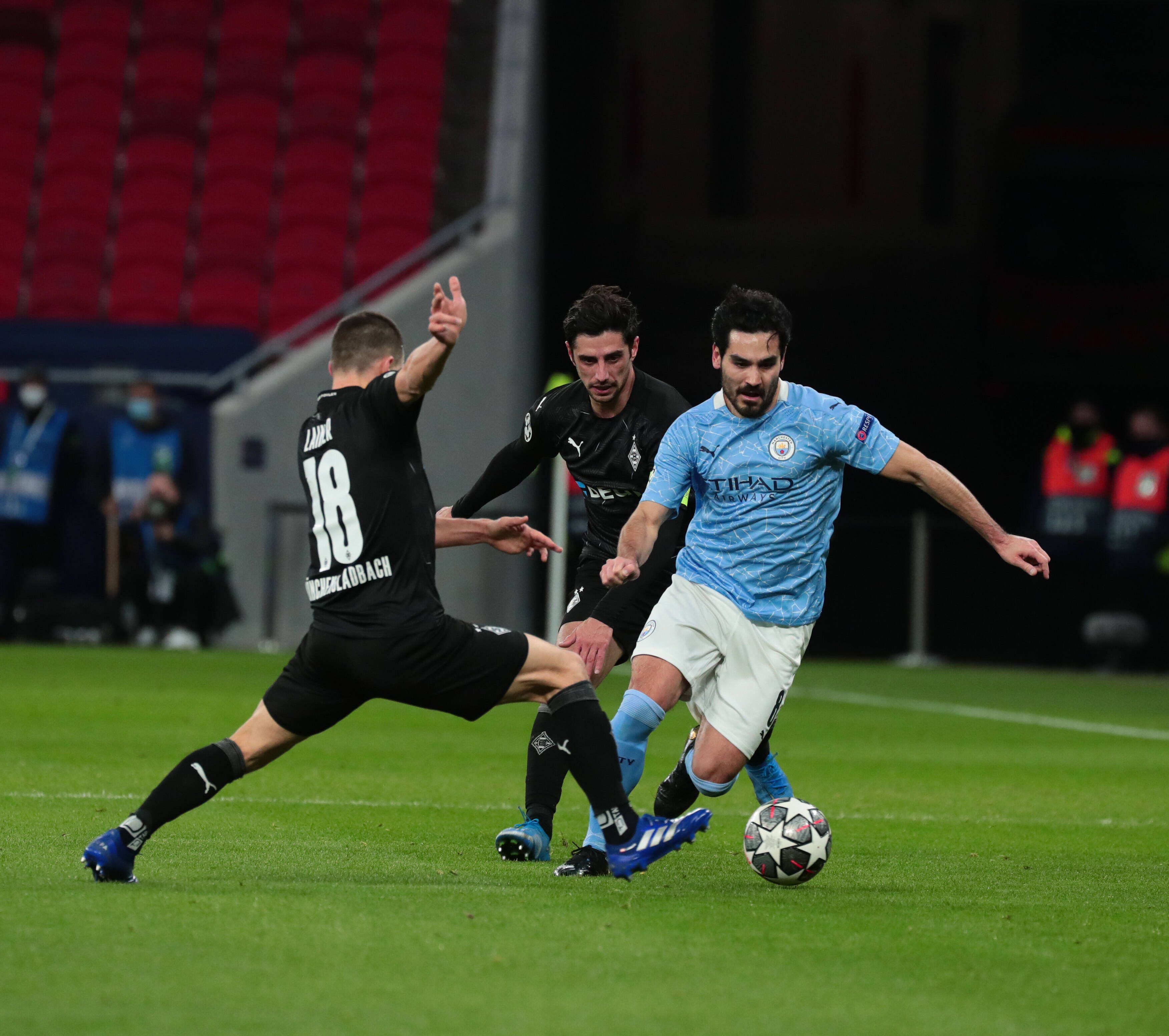 Gladbachs Stefan Lainer (l.) und Kapitän Lars Stindl versuchen im Champions League-Spiel der Gladbacher gegen Manchester City am 16. März 2021 ihren Gegenspieler Ilkay Gündogan (r.) zu stoppen.