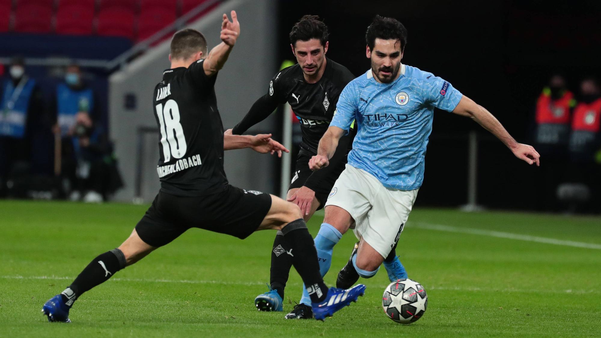 Gladbachs Stefan Lainer (l.) und Kapitän Lars Stindl versuchen im Champions League-Spiel der Gladbacher gegen Manchester City am 16. März 2021 ihren Gegenspieler Ilkay Gündogan (r.) zu stoppen.
