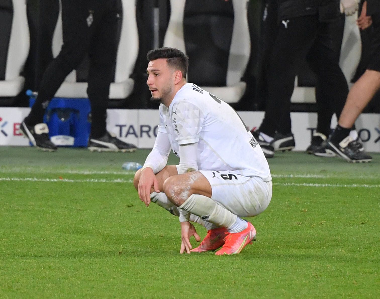 Borussias Ramy Bensebaini hockt nach dem Pokal-Aus seines Teams gegen Dortmund am 3. März 2021 enttäuscht auf dem Feld.