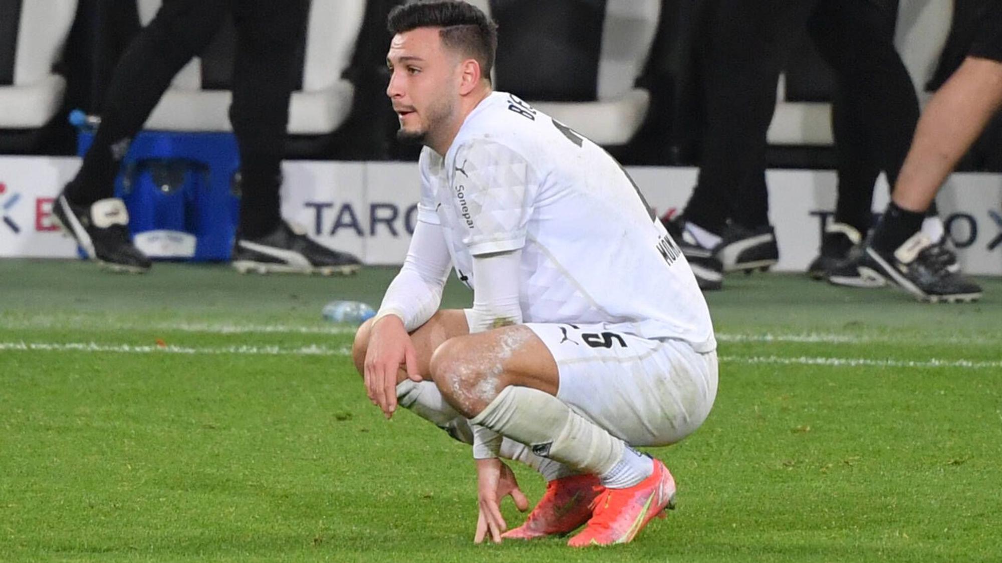 Borussias Ramy Bensebaini hockt nach dem Pokal-Aus seines Teams gegen Dortmund am 3. März 2021 enttäuscht auf dem Feld.
