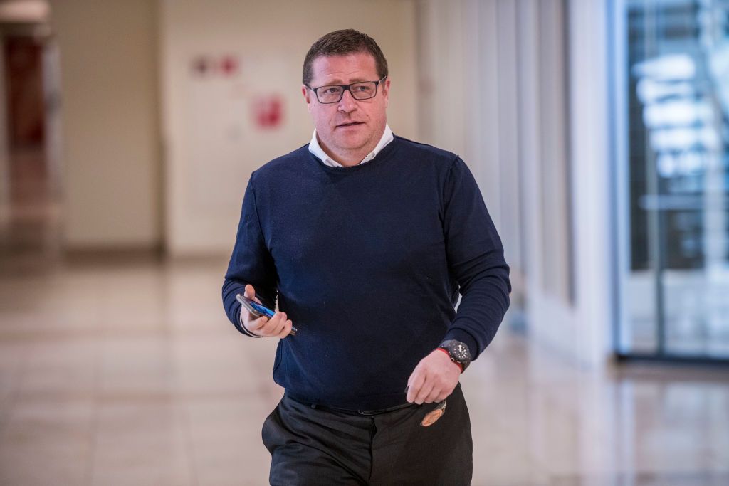 Gladbach-Manager Max Eberl schreitet voran und hält in seiner rechten Hand ein Smartphone.