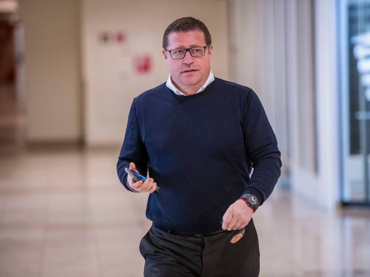 Gladbach-Manager Max Eberl schreitet voran und hält in seiner rechten Hand ein Smartphone.