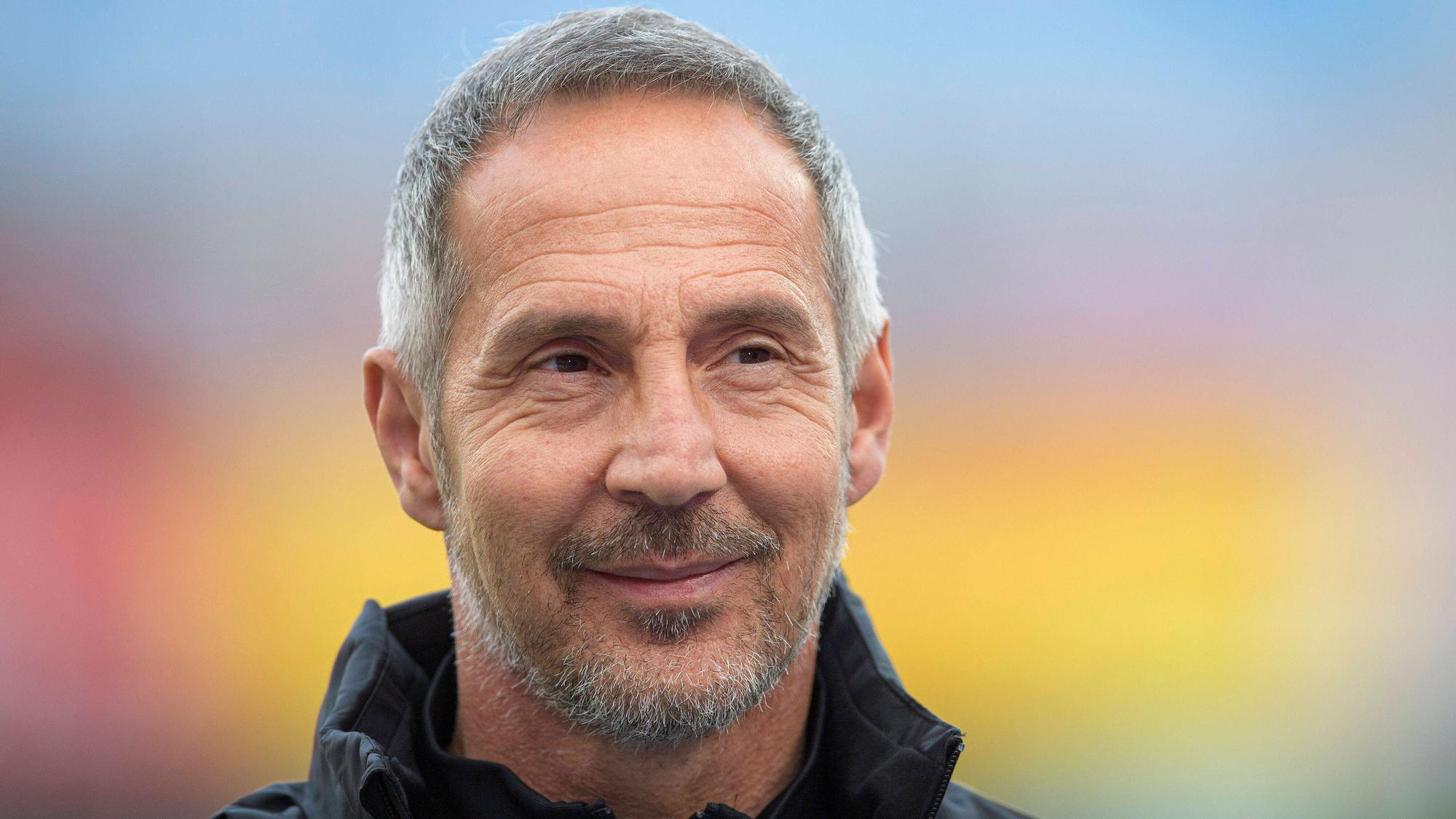 Trainer Adi Hütter macht ein freundliches Gesicht und lächelt in die Kamera.
