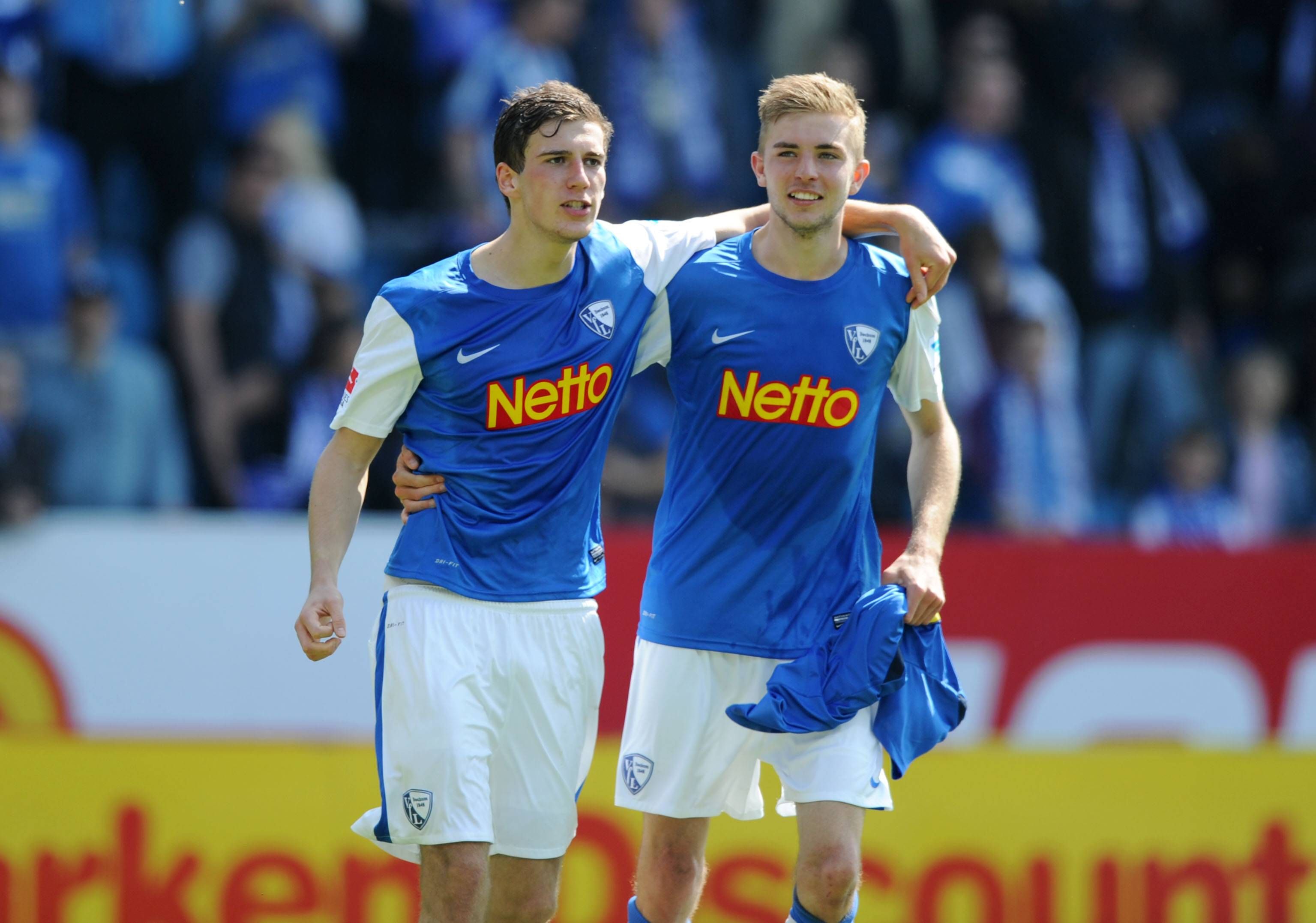 Leon Goretzka (l.) hat den Arm um Christoph Kramers Schultern gelegt, beide Fußballspieler lachen.