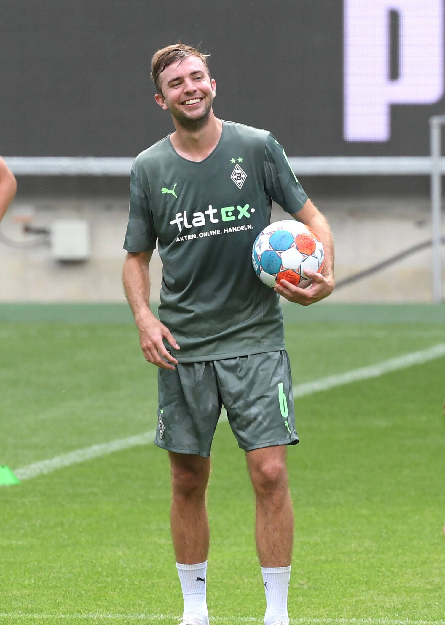 Gladbachs Christoph Kramer hält mit lachendem Gesicht einen Fußball unterm Arm.