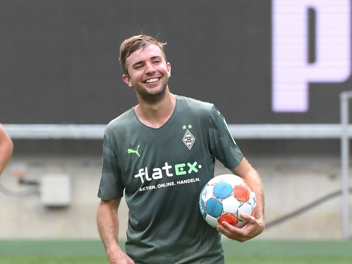 Gladbachs Christoph Kramer hält mit lachendem Gesicht einen Fußball unterm Arm.
