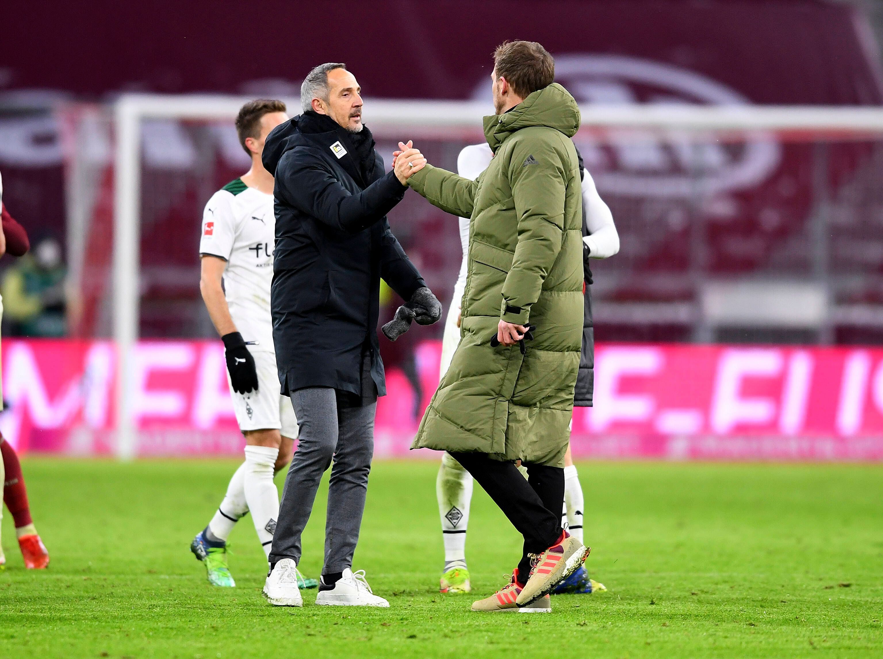 Gladbach-Trainer Adi Hütter (l.) klatscht zum Rückrundenauftakt (7. Januar 2022) in der Allianz-Arena Bayern-München-Coach Julian Nagelsmann (r.) ab. Beide Trainer tragen warme Jacken.
