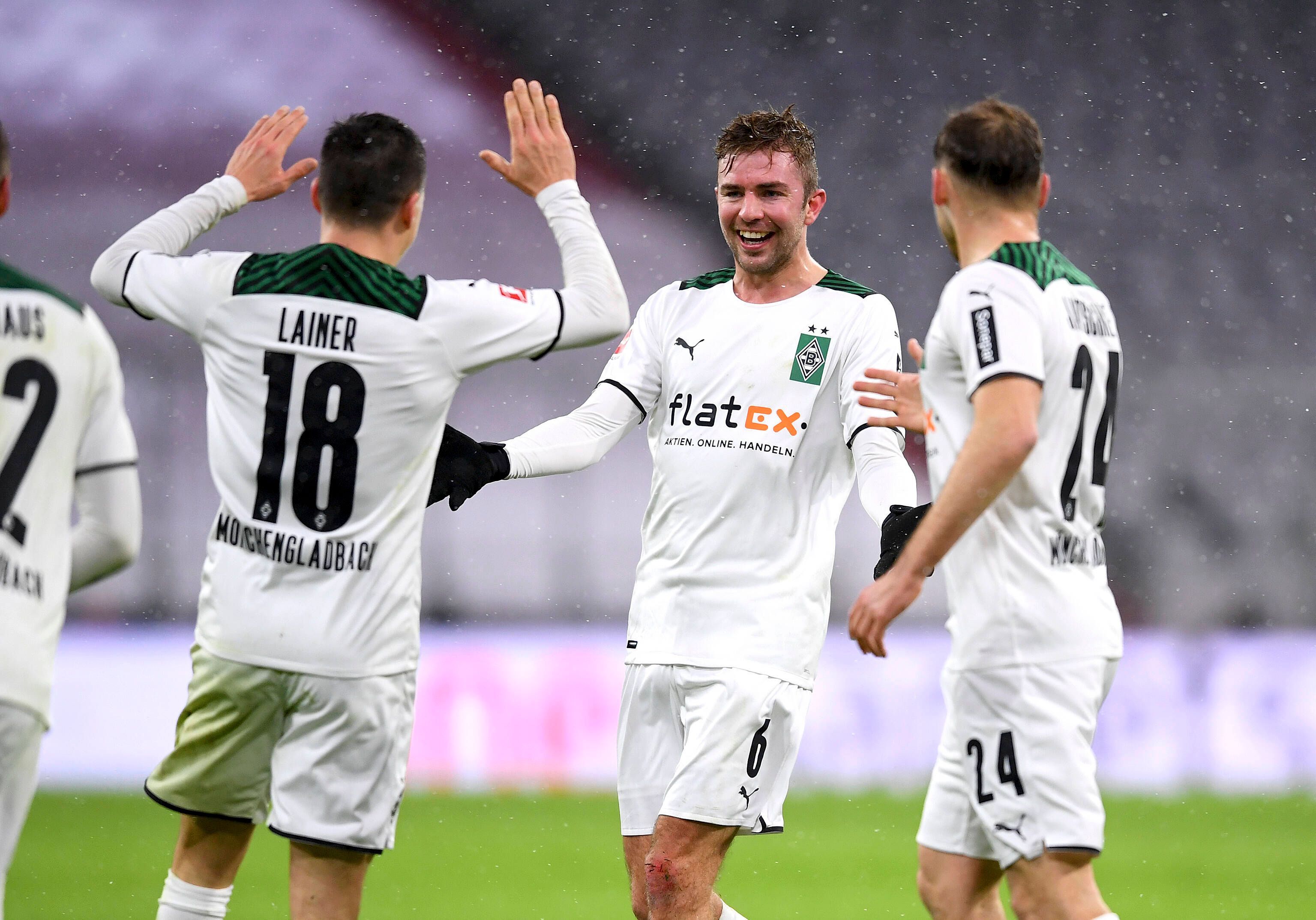 Christoph Kramer (M.) bejubelt mit Stefan Lainer (l.) und Tony Jantschke (r.) den 2:1-Siegtreffer von Borussia Mönchengladbach zum Bundesliga-Rückrundenauftakt (7. Januar 2021) bei Bayern München. Kramer lacht und breitet die Arme aus.