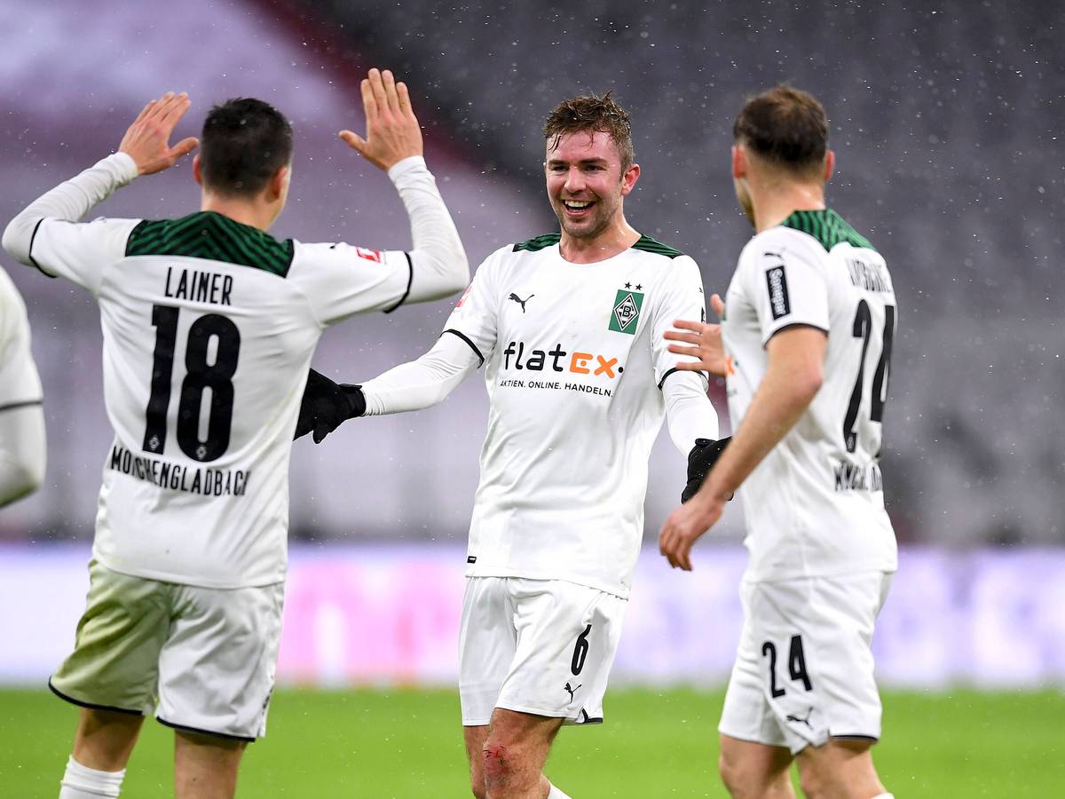Christoph Kramer (M.) bejubelt mit Stefan Lainer (l.) und Tony Jantschke (r.) den 2:1-Siegtreffer von Borussia Mönchengladbach zum Bundesliga-Rückrundenauftakt (7. Januar 2021) bei Bayern München. Kramer lacht und breitet die Arme aus.