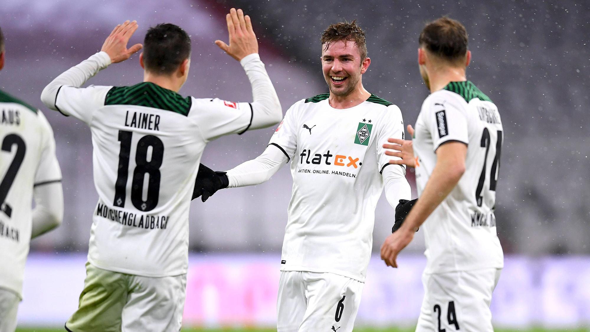 Christoph Kramer (M.) bejubelt mit Stefan Lainer (l.) und Tony Jantschke (r.) den 2:1-Siegtreffer von Borussia Mönchengladbach zum Bundesliga-Rückrundenauftakt (7. Januar 2021) bei Bayern München. Kramer lacht und breitet die Arme aus.