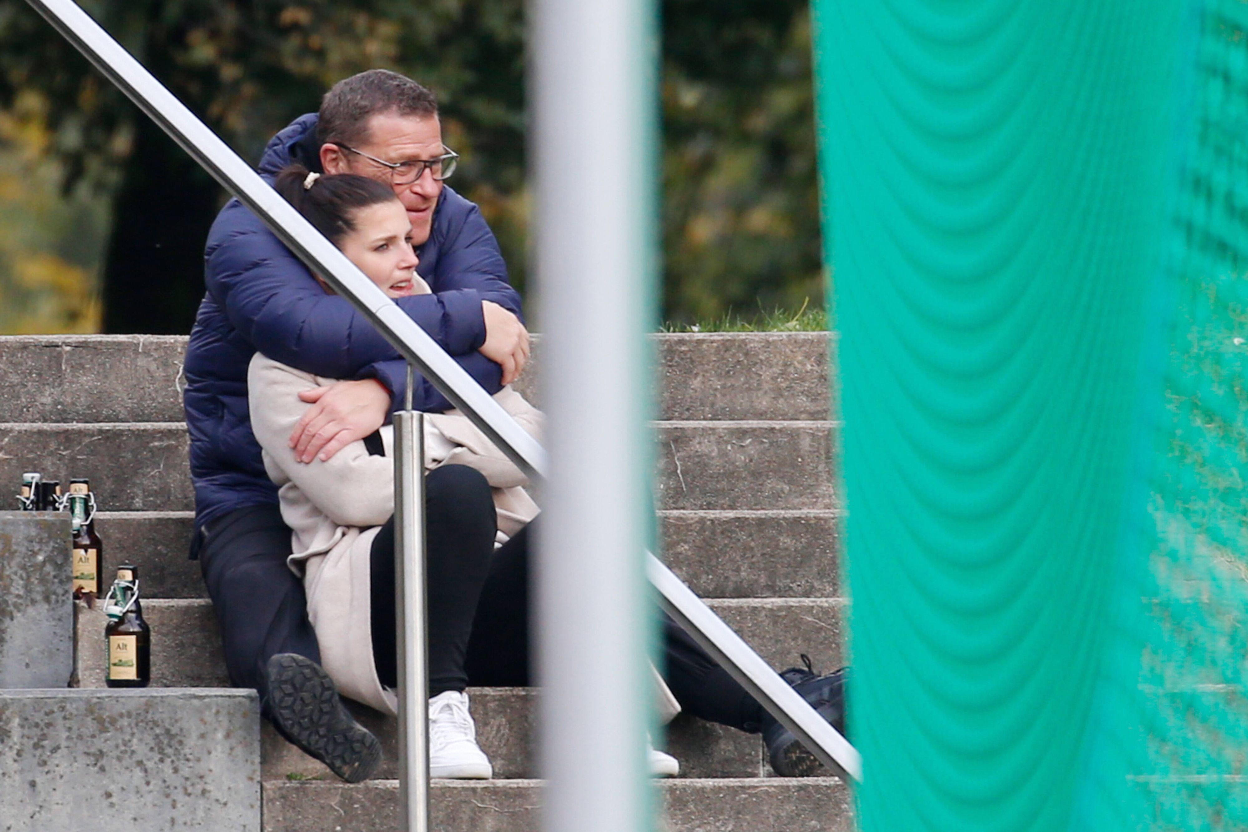 Max Eberl, Manager von Borussia Mönchengladbach, schaut sich in Viersen gemeinsam mit der ehemaligen Assistenz-Teammanagerin des VfL, Sedrina Schaller, am 17. Oktober 2021 das Landesliga-Spiel zwischen ASV Süchteln gegen SC Kapellen-Erft an. Max Eberl umarmt von hinten Sedrina Schaller.