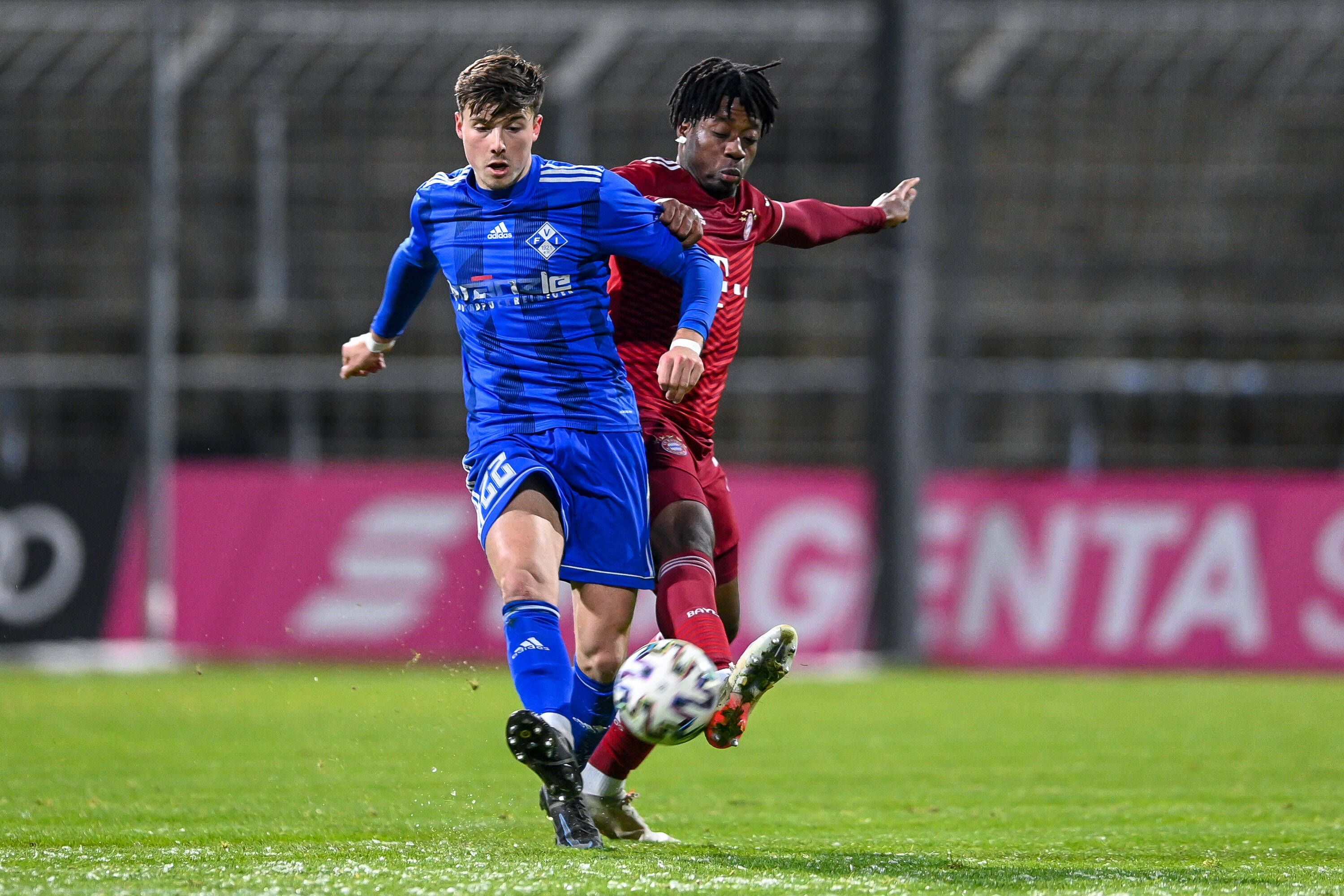 Semir Telalovic (l.) von FV Illertissen, hier am 3. Dezember 2021 in der Regionalliga Bayern im Duell mit Bright Akwo Arrey-Mbi (r.) von Bayern München II, steht vor einem Wechsel zu Borussia Mönchengladbach. Telalovic schießt den Ball nach vorne.