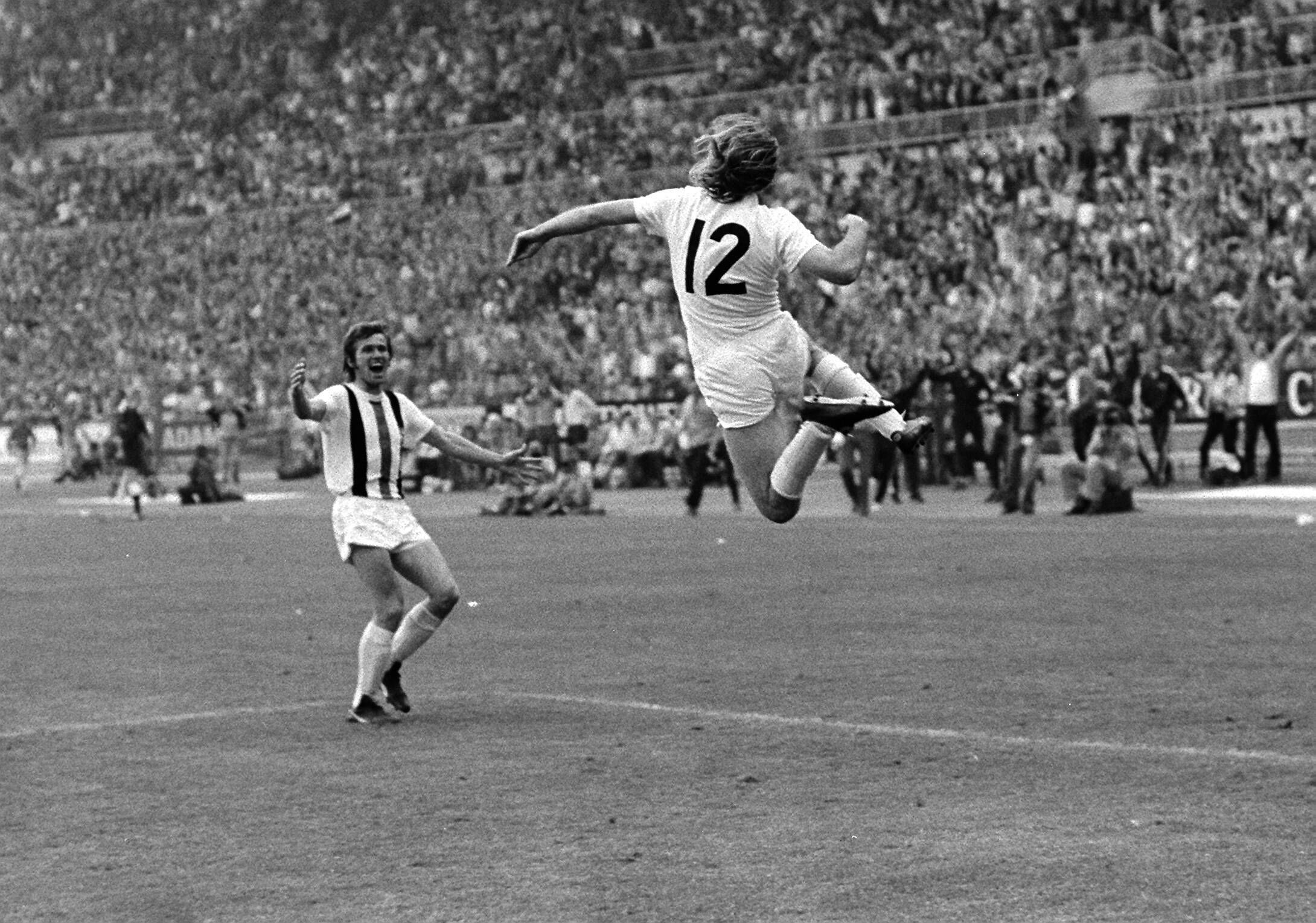 Günter Netzer (r.) springt nach seinem sensationellen Siegtreffer im DFB-Pokal-Finale am 23. Juni 1973 gegen den Erzrivalen 1. FC Köln seinem Borussia-Mönchengladbach-Team-Kollegen Jupp Heynckes (l.) im Düsseldorfer Rheinstadion in die Arme. Beide jubeln ausgelassen.