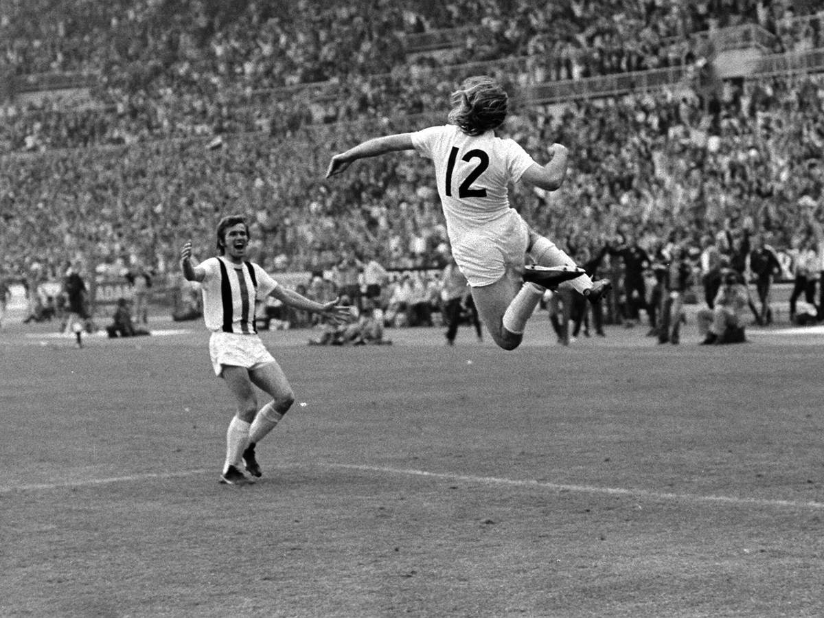 Günter Netzer (r.) springt nach seinem sensationellen Siegtreffer im DFB-Pokal-Finale am 23. Juni 1973 gegen den Erzrivalen 1. FC Köln seinem Borussia-Mönchengladbach-Team-Kollegen Jupp Heynckes (l.) im Düsseldorfer Rheinstadion in die Arme. Beide jubeln ausgelassen.