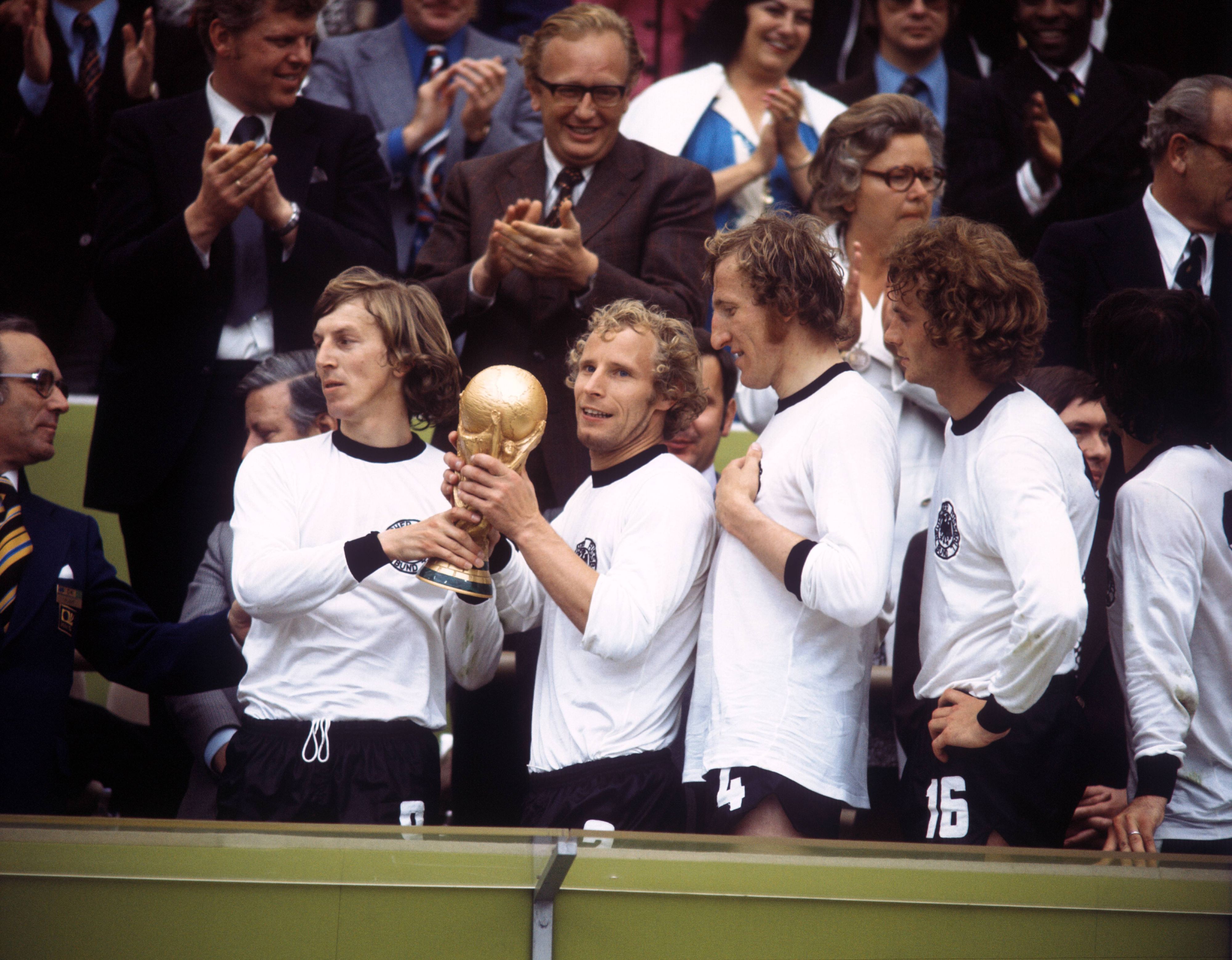 Gladbachs Rekordspieler Berti Vogts (2.v.l.) hält am 7. Juli 1974 im Münchner Olympiastadion nach dem Endspielsieg gegen die Niederlande stolz den Weltmeister-Pokal in seinen Händen. Rechts ist auch Gladbach-Legende Rainer Bonhof zu sehen.