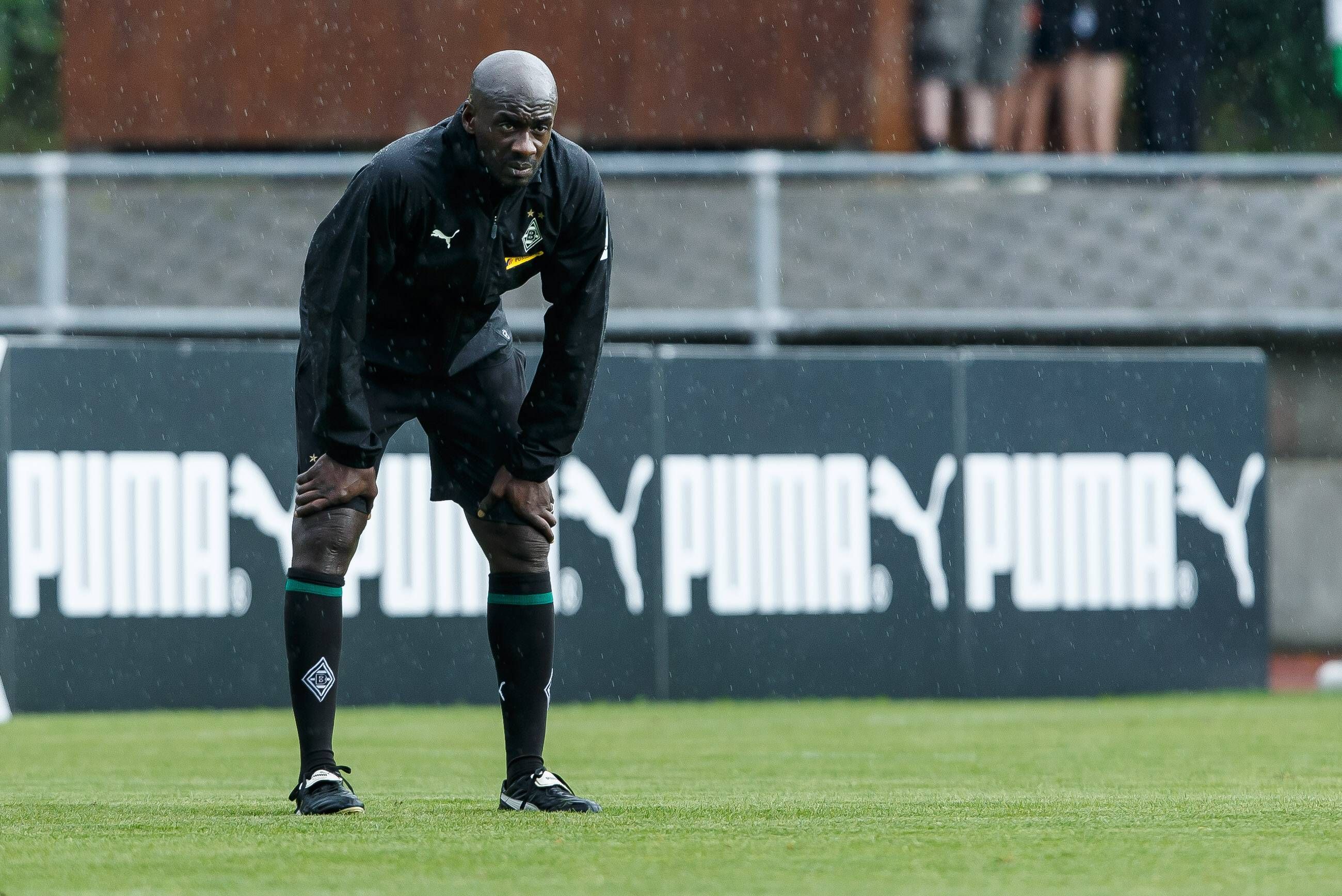 Otto Addo als Co-Trainer von Borussia Mönchengladbach während des Fohlen-Trainingslagers am 25. Juli 2018 in Rottach-Egern am Tegernsee. Addo hat sich nach vorne gebeugt und schaut über das Spielfeld.