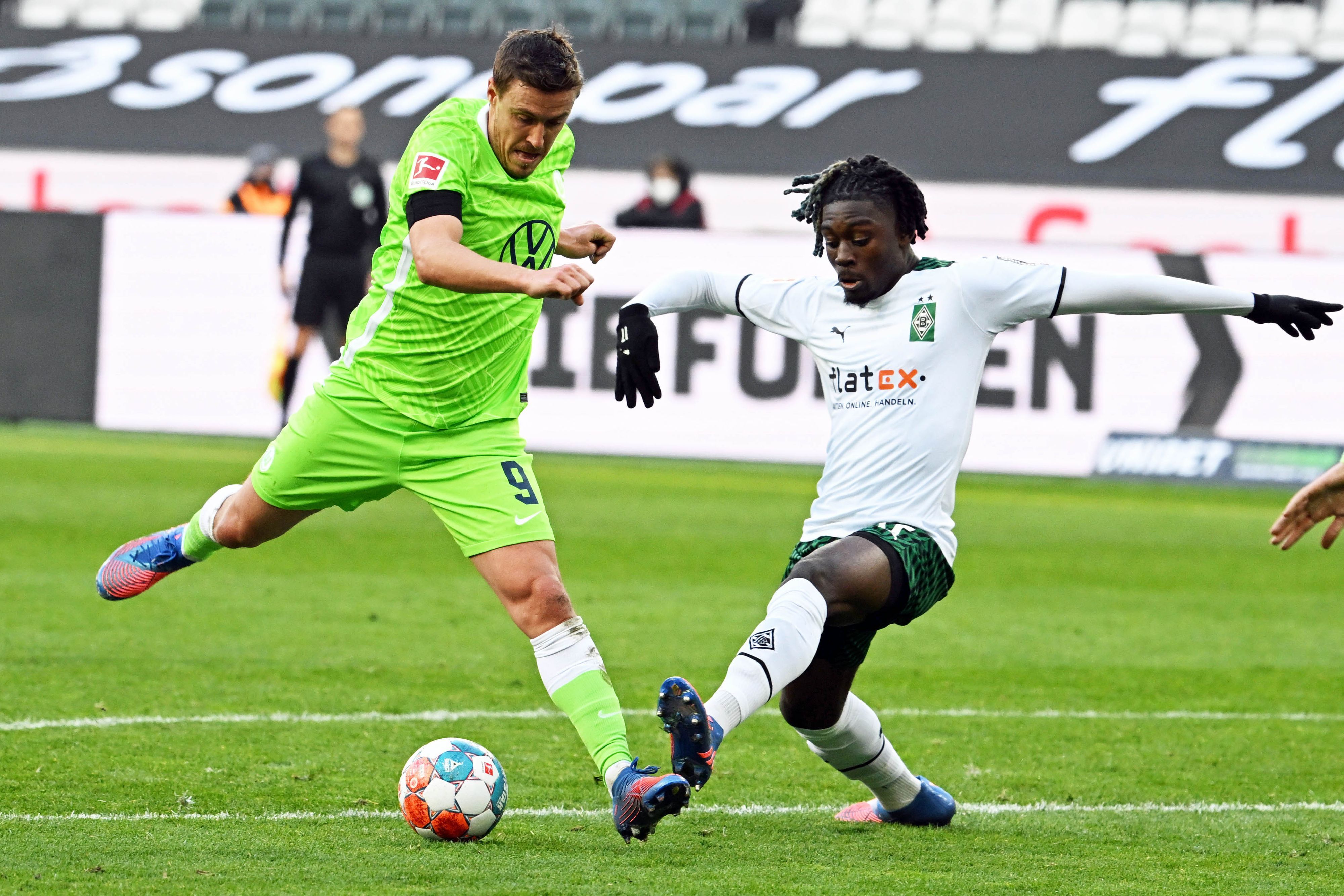 Manu Koné (r.) von Borussia Mönchengladbach im Zweikampf mit Max Kruse (l.) vom VfL Wolfsburg während des Bundesliga-Duells.