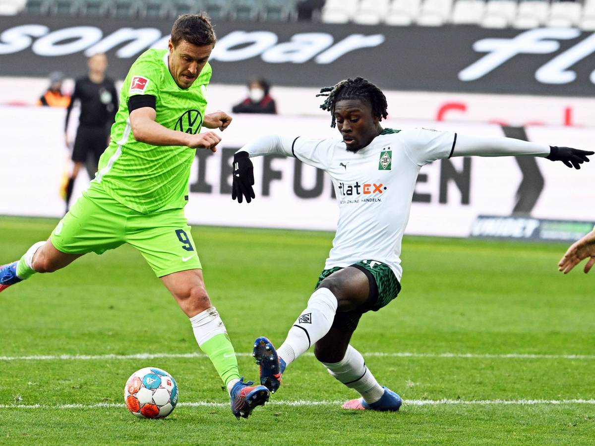 Manu Koné (r.) von Borussia Mönchengladbach im Zweikampf mit Max Kruse (l.) vom VfL Wolfsburg während des Bundesliga-Duells.
