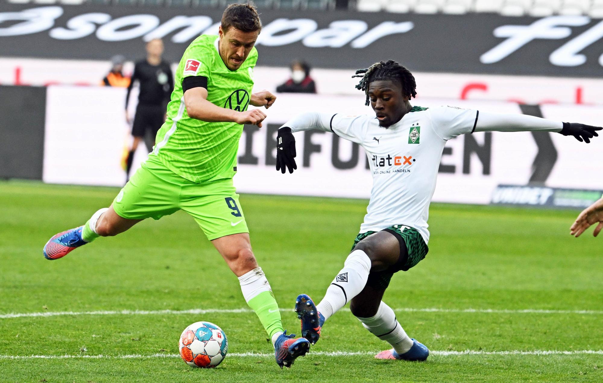 Manu Koné (r.) von Borussia Mönchengladbach im Zweikampf mit Max Kruse (l.) vom VfL Wolfsburg während des Bundesliga-Duells.
