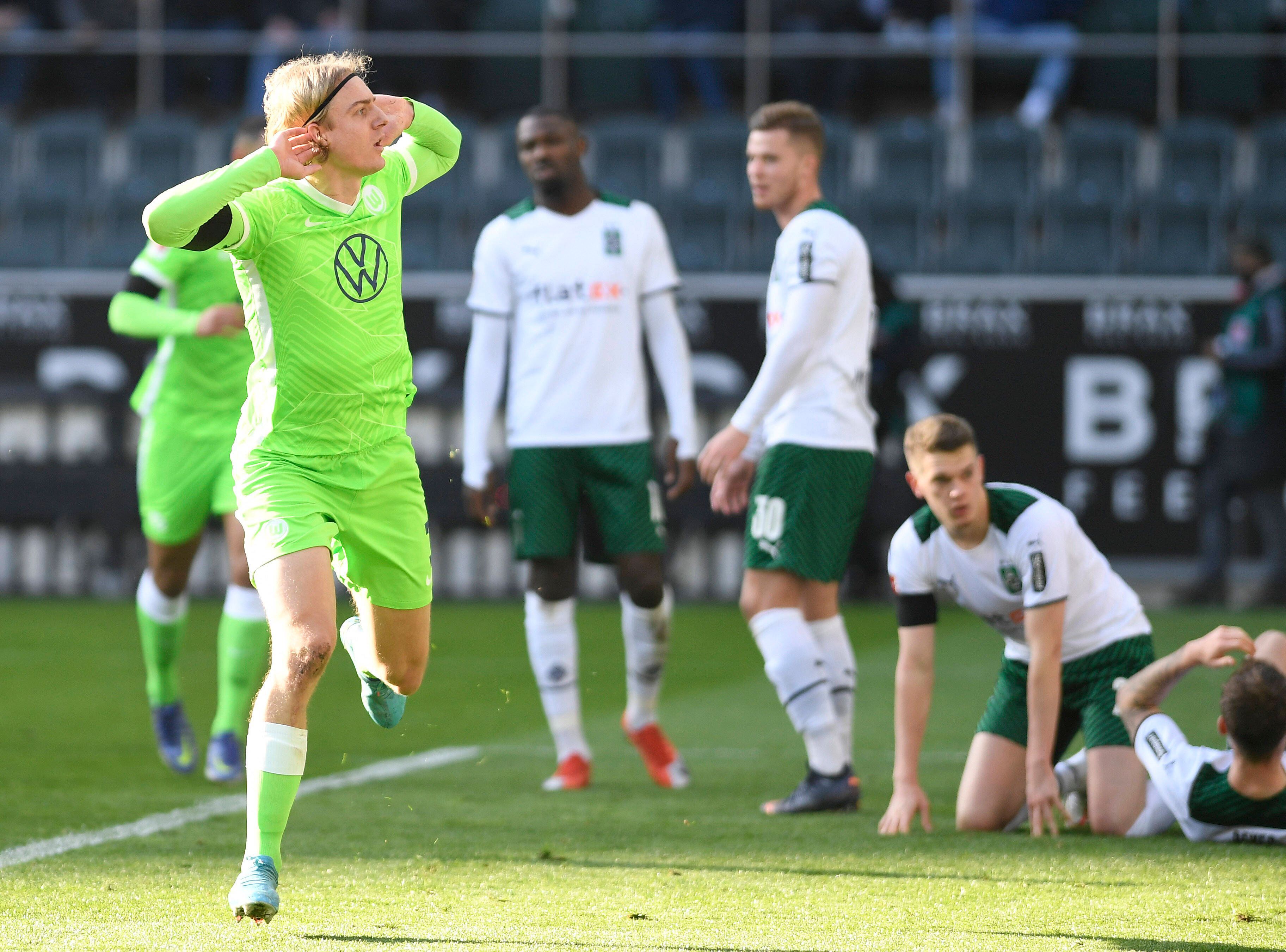 Sebastiaan Bornauw vom VfL Wolfsburg macht eine provokative Geste in Richtung der Fohlen-Fans in der Nordkurve während des Bundesliga-Duells (26. Februar 2022) gegen Borussia Mönchengladbach. Bornauw hält die Hände an die Ohren.