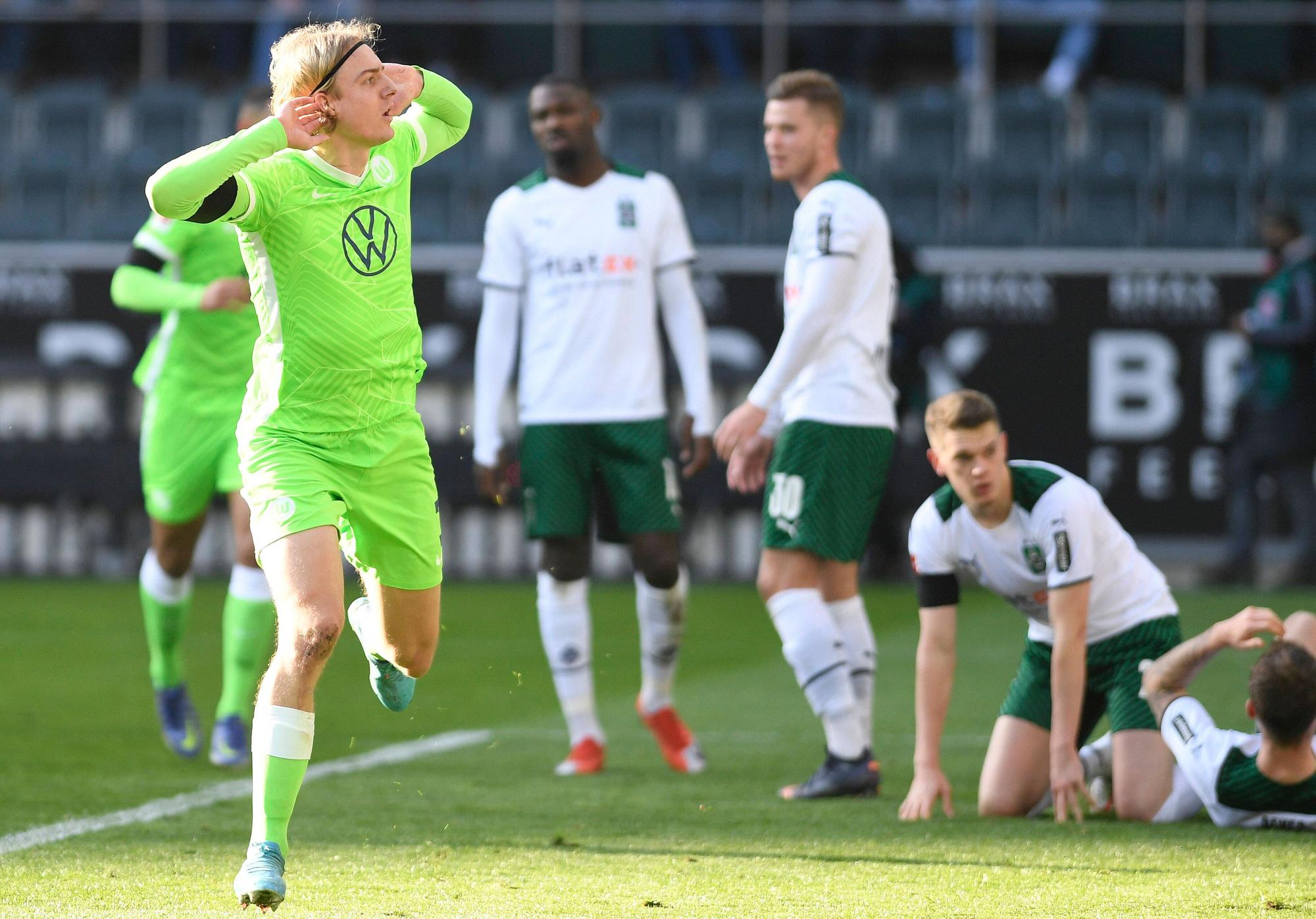 Sebastiaan Bornauw vom VfL Wolfsburg macht eine provokative Geste in Richtung der Fohlen-Fans in der Nordkurve während des Bundesliga-Duells (26. Februar 2022) gegen Borussia Mönchengladbach. Bornauw hält die Hände an die Ohren.