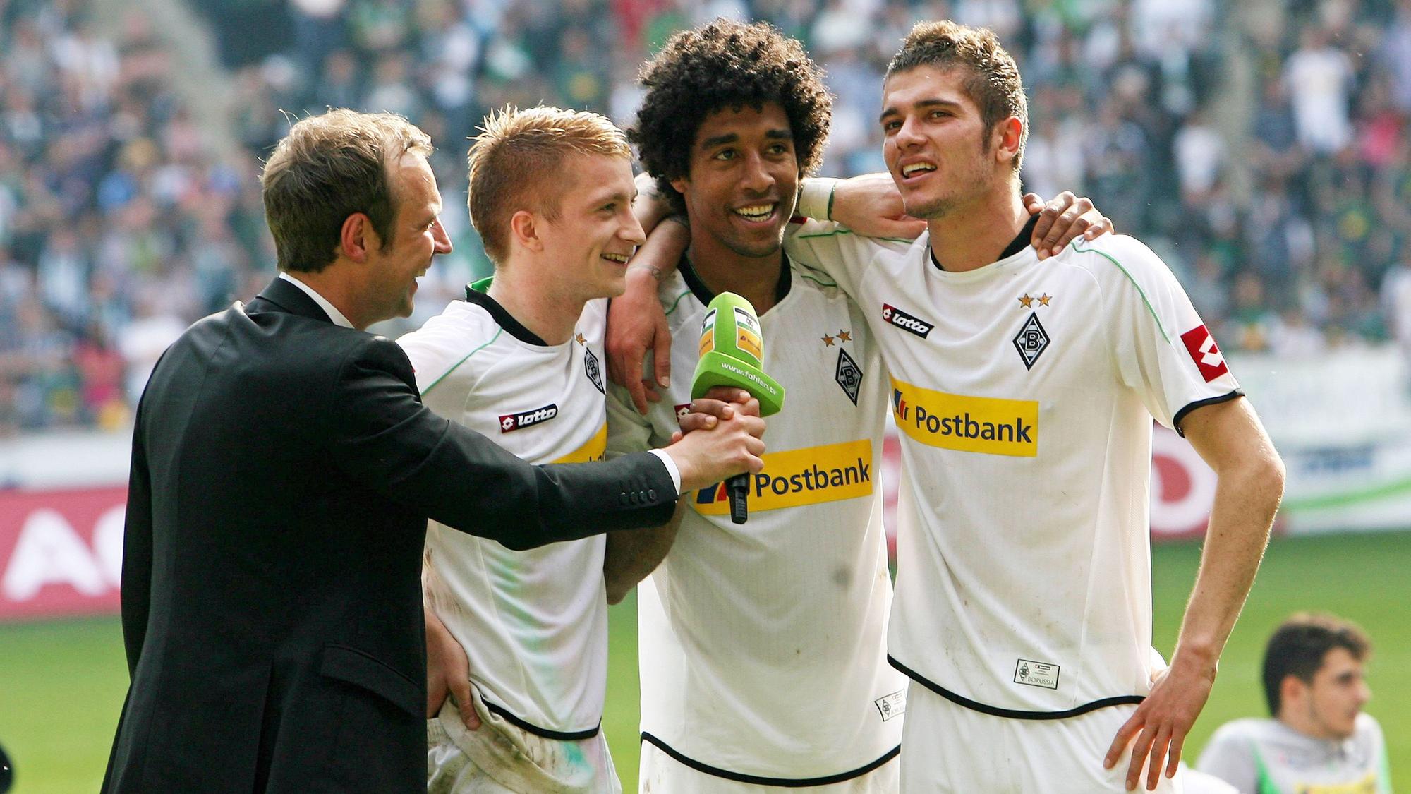 Die ehemaligen Gladbach-Profis (v.r.) Roman Neustädter, Dante und Marco Reus im Gespräch mit Stadionsprecher Torsten Knippertz (l.) am 28. April 2012 im Borussia-Park. Knippertz hält das Stadion-Mikrofon, die Spieler umarmen sich.
