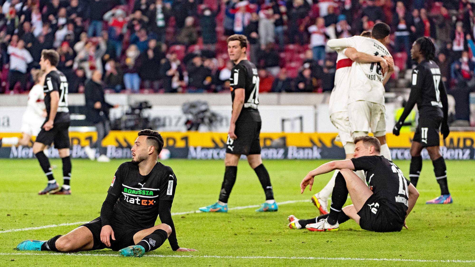 Jubelnde Stuttgarter, gefrustete Gladbach-Spieler wie Ramy Bensebaini (l.) oder Matthias Ginter (r.) beim Bundesliga-Duell am 5. März 2022 in der Mercedes-Benz-Arena. Bensebaini und Ginter sitzen enttäuscht auf dem Spielfeld.