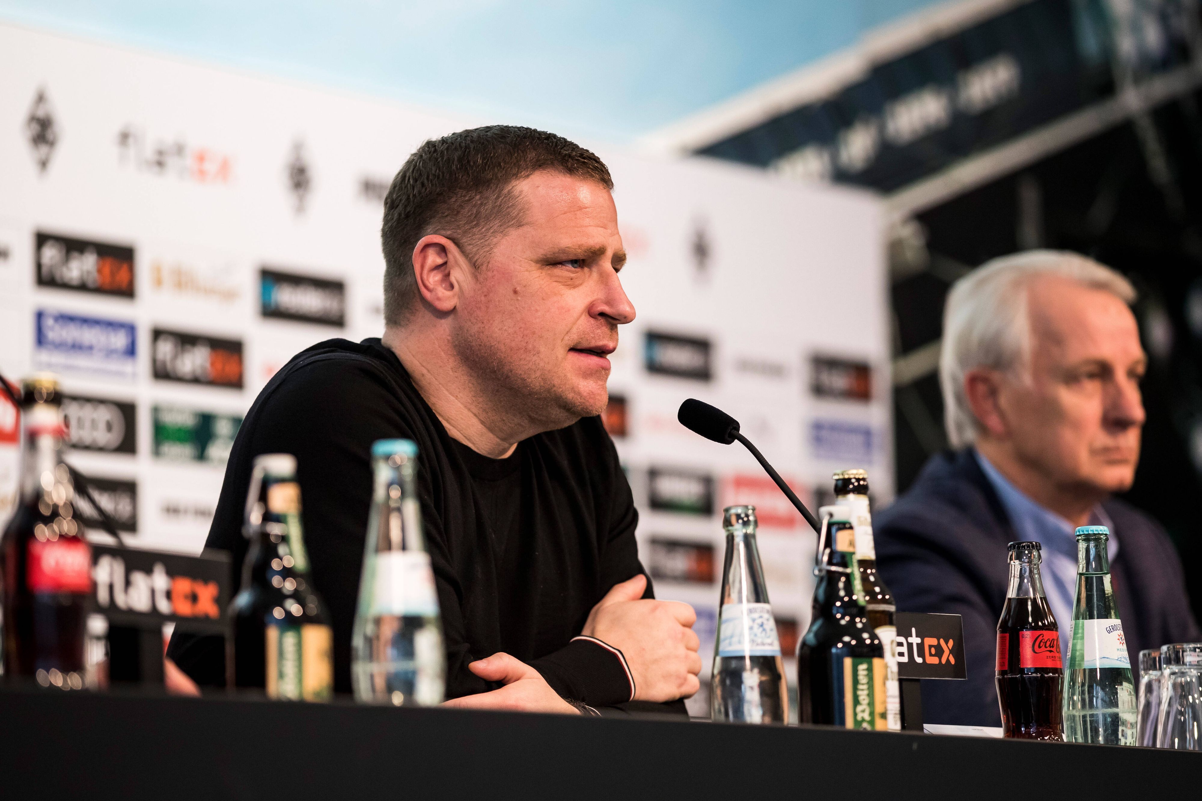 Max Eberl (l.) und Rainer Bonhof (r.) während der Pressekonferenz von Borussia Mönchengladbach vom 28.01.2022. Eberl spricht ins Mikrofon.
