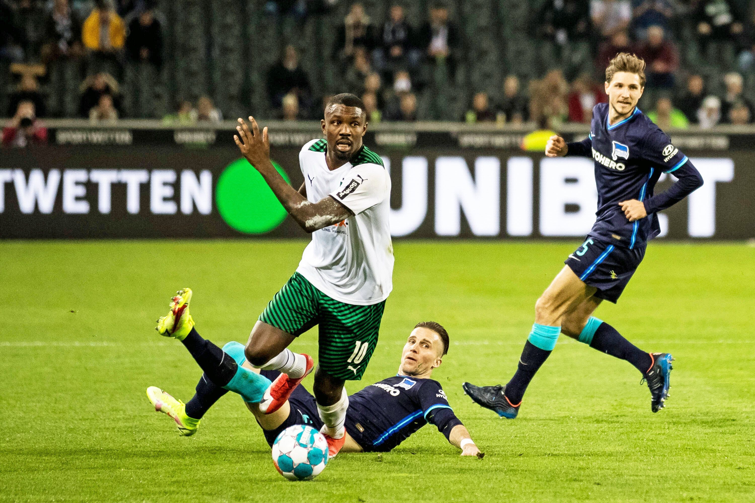 Gladbach-Stürmer Marcus Thuram (M.) setzt sich gegen zwei Berliner Gegenspieler im Bundesliga-Duell (12. März 2022) im Borussia-Park durch. Thuram schaut nach vorne.