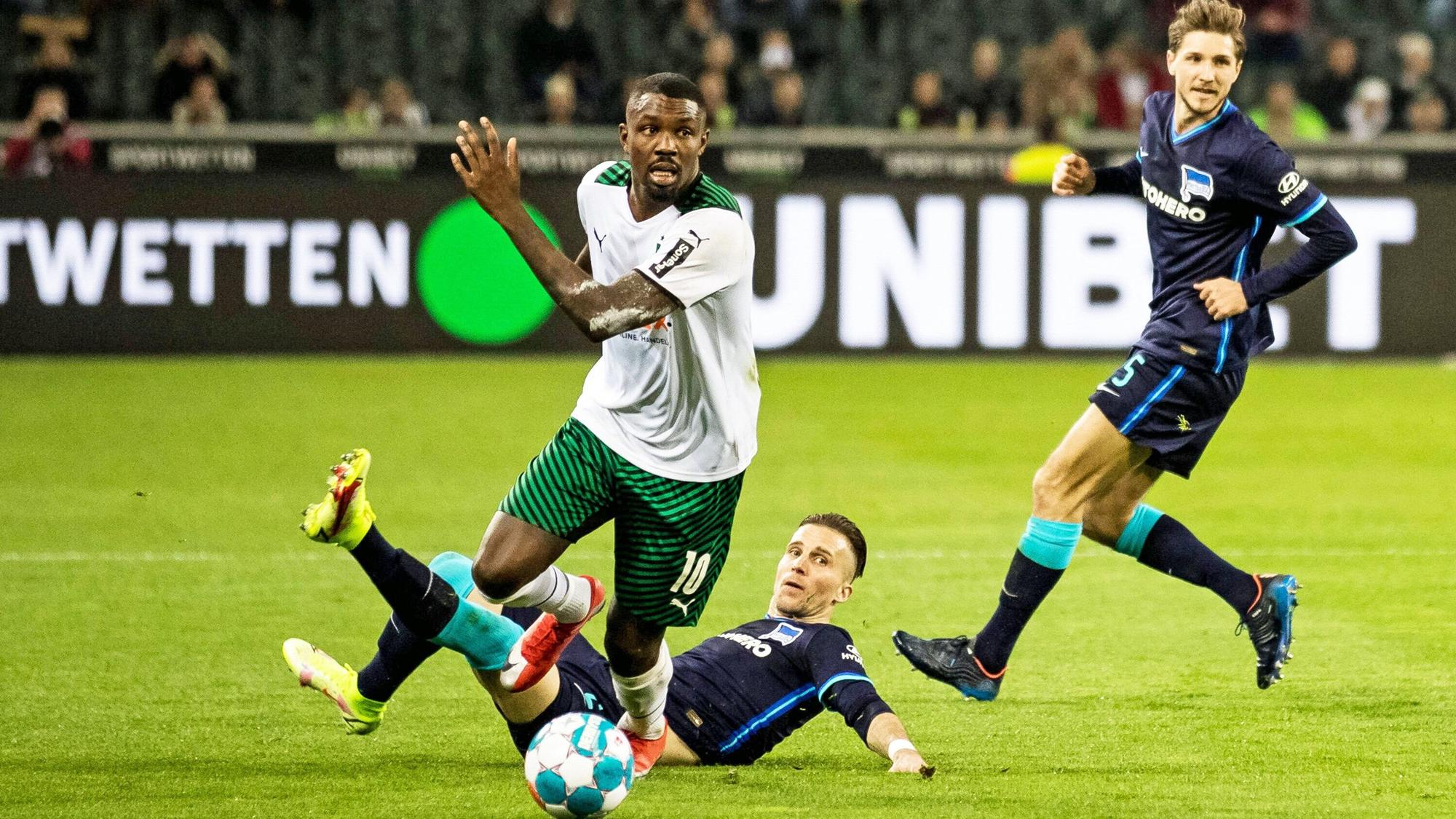 Gladbach-Stürmer Marcus Thuram (M.) setzt sich gegen zwei Berliner Gegenspieler im Bundesliga-Duell (12. März 2022) im Borussia-Park durch. Thuram schaut nach vorne.