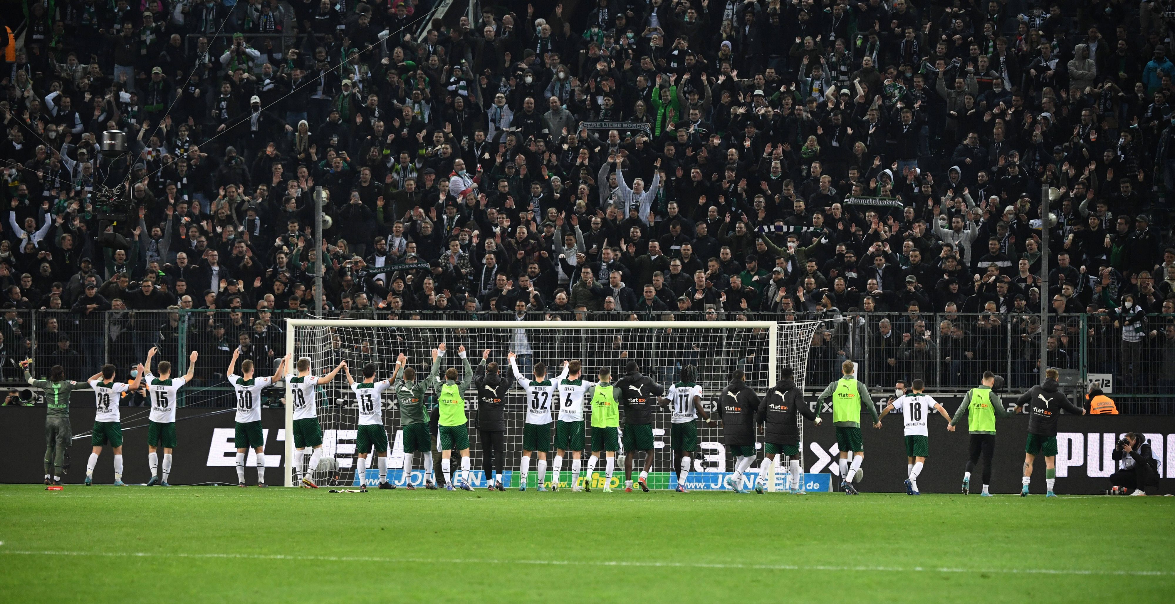 Die Spieler von Borussia Mönchengladbach feiern am Samstag (12. März 2022) gemeinsam mit den Fans den Heimsieg im Abstiegskampf gegen Hertha BSC. Die Gladbach-Spieler bilden eine Kette und heben gemeinsam die Arme.